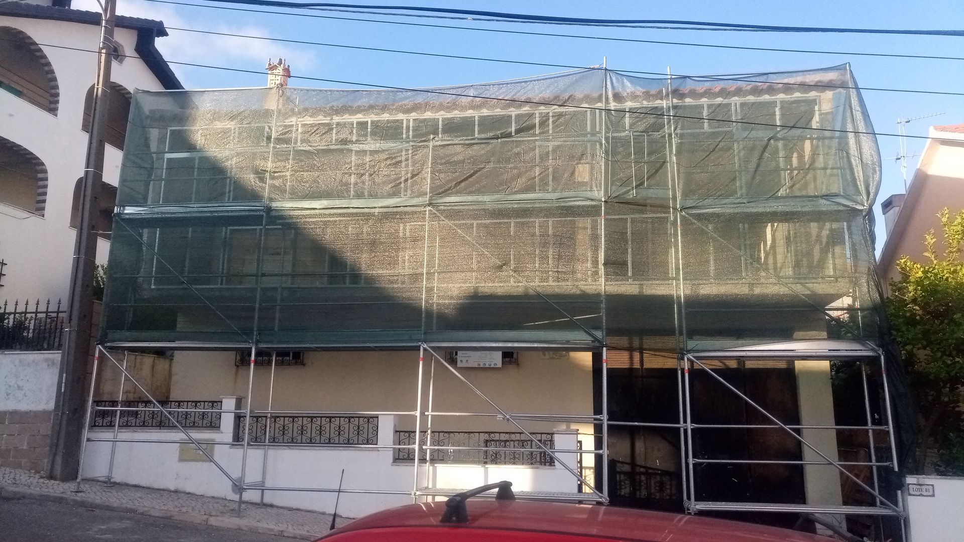 Prédio em reforma, coberto por andaimes e tela verde.