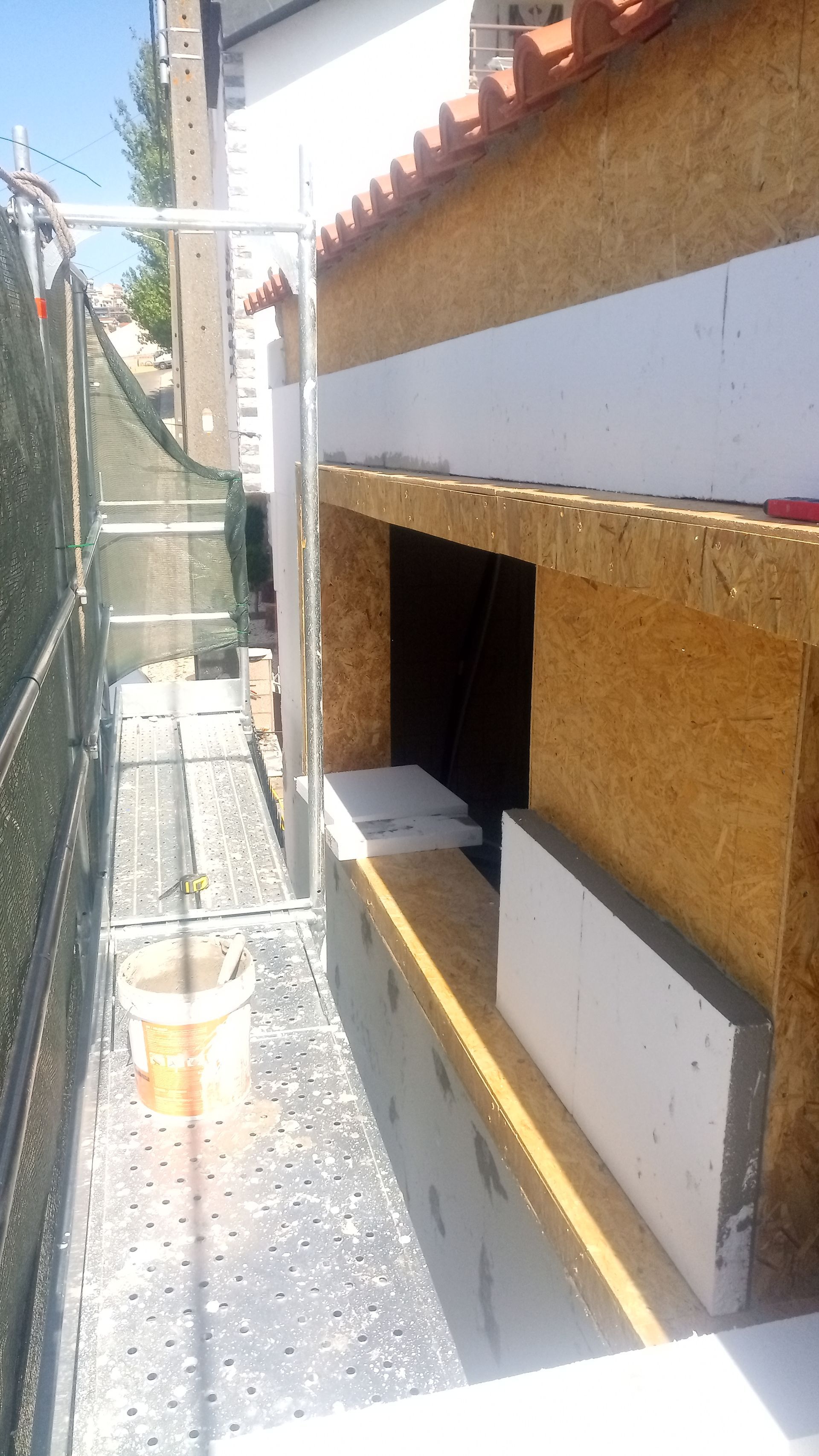 Parede externa em construção com andaimes, isolamento e painéis OSB.