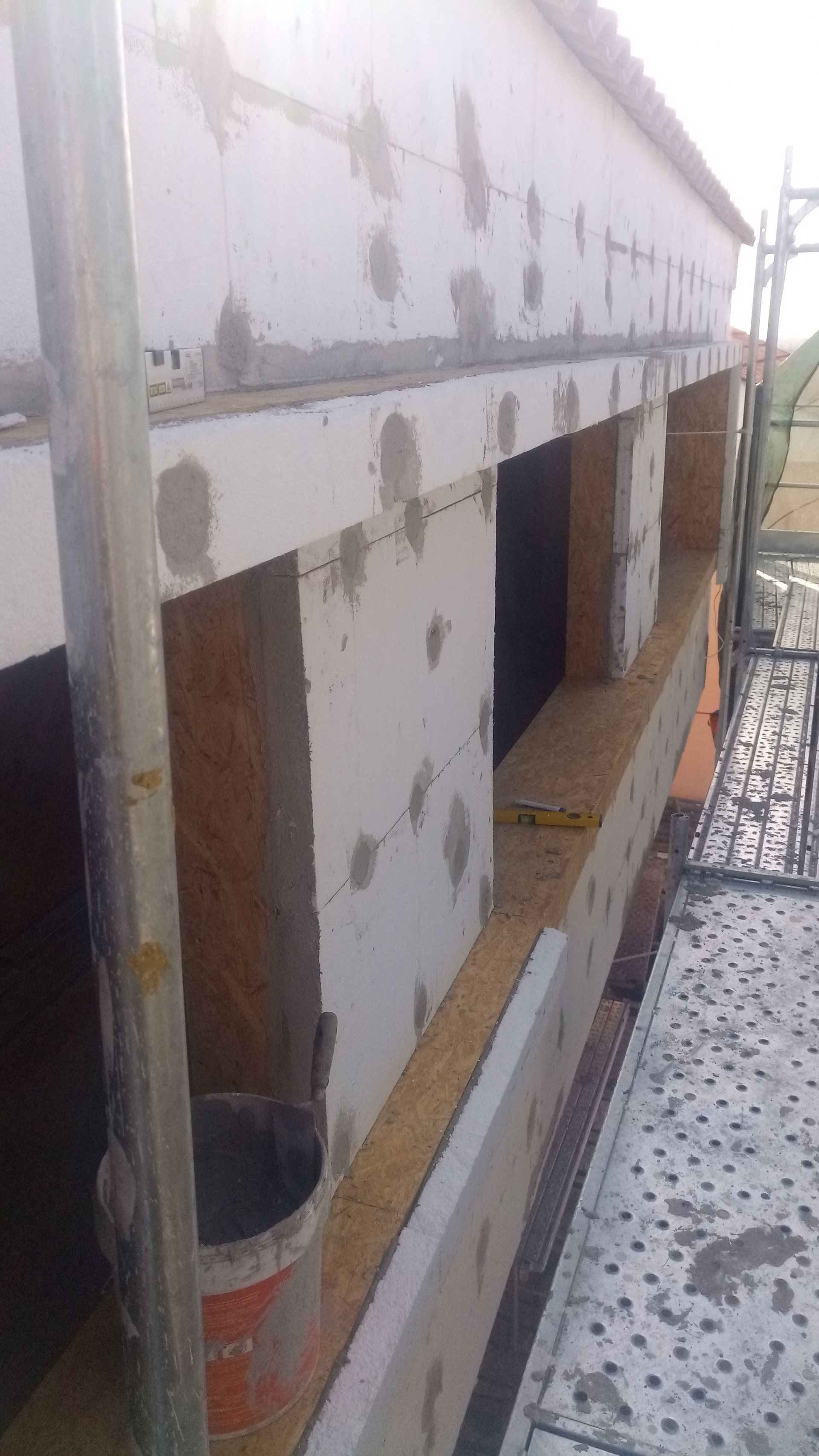 Construção de paredes externas com isolamento, argamassa e andaimes.