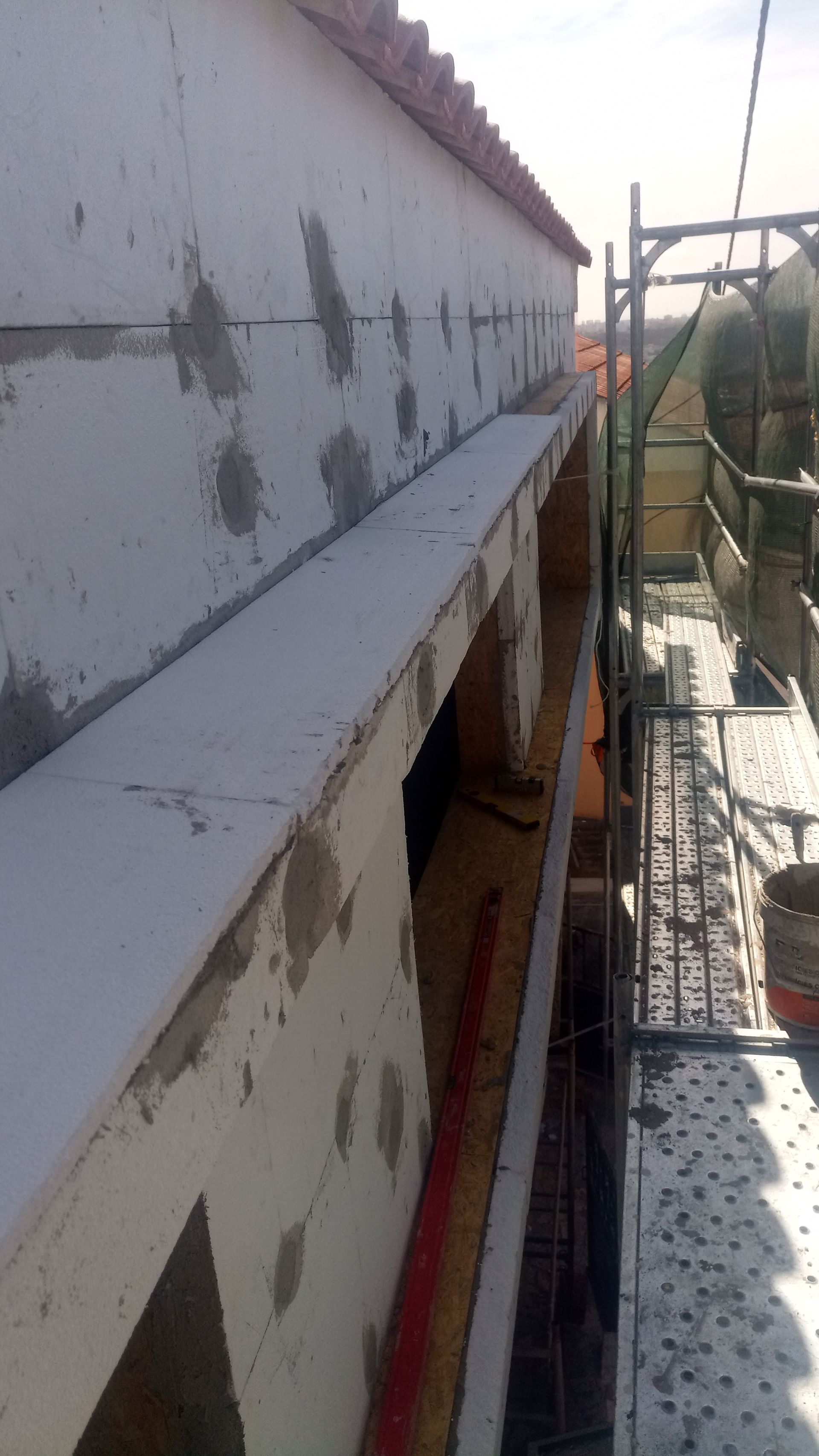 Construção exterior: parede isolada com uma saliência, andaimes ao fundo.