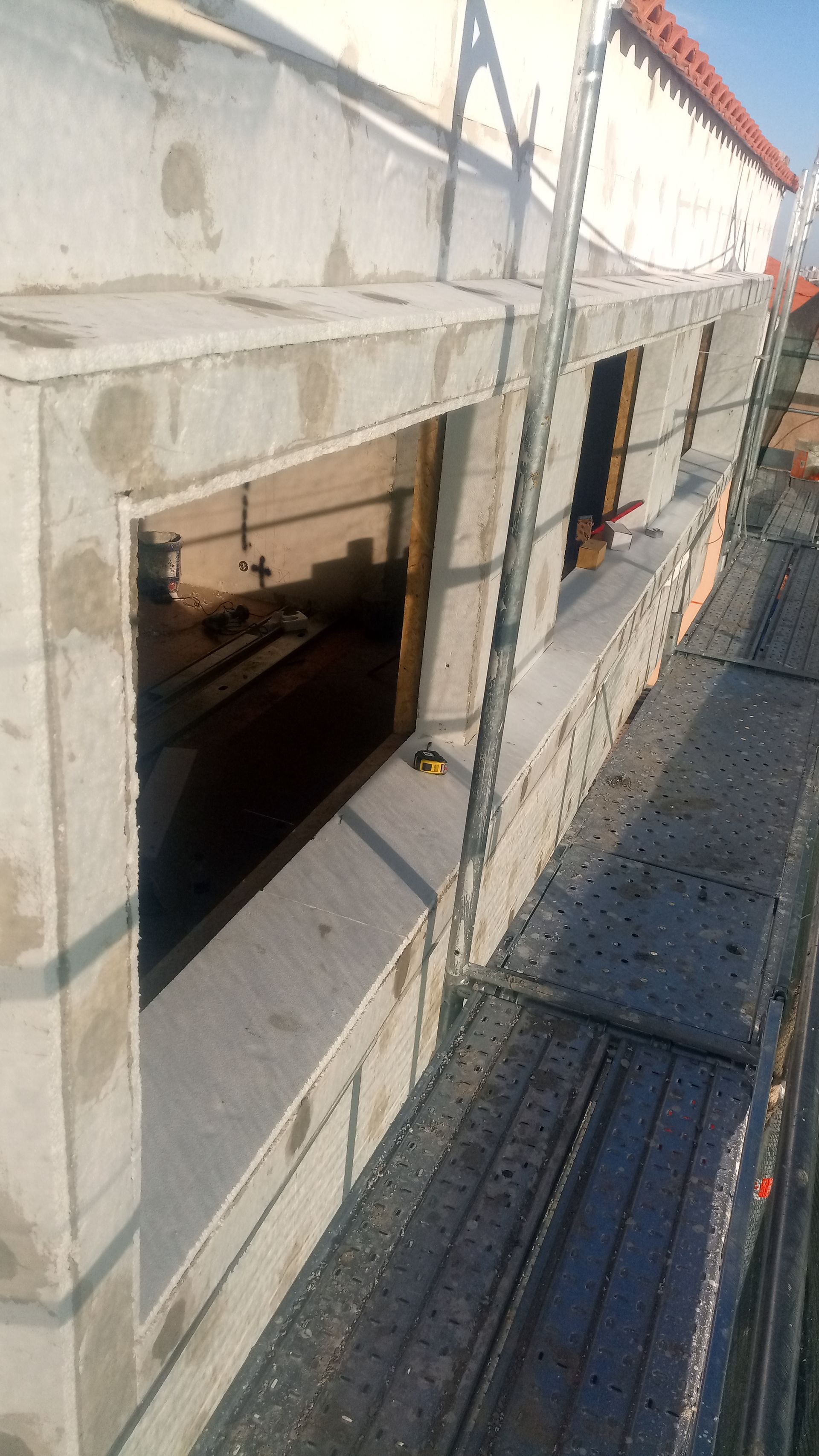 Canteiro de obras: caixilhos de janelas de concreto, andaimes e parede externa.