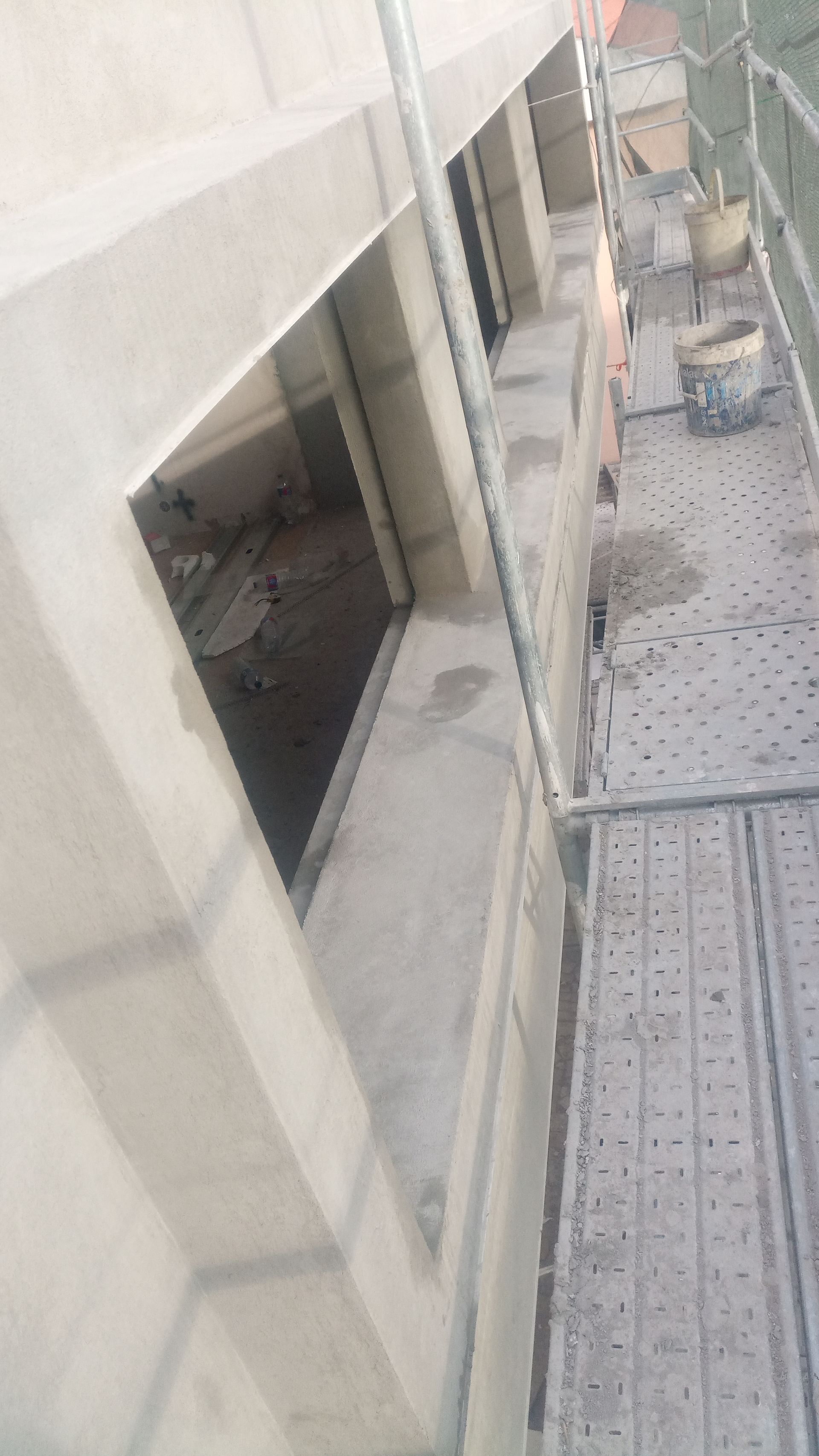 Exterior de um canteiro de obras, com uma janela aberta e um andaime ao lado.