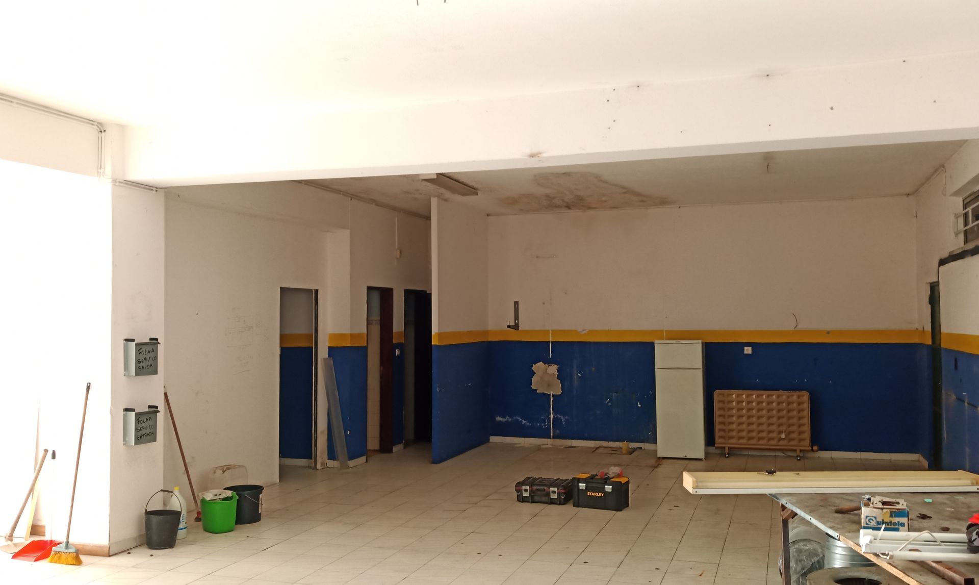 Interior vazio, paredes azuis e brancas, cômodo inacabado.