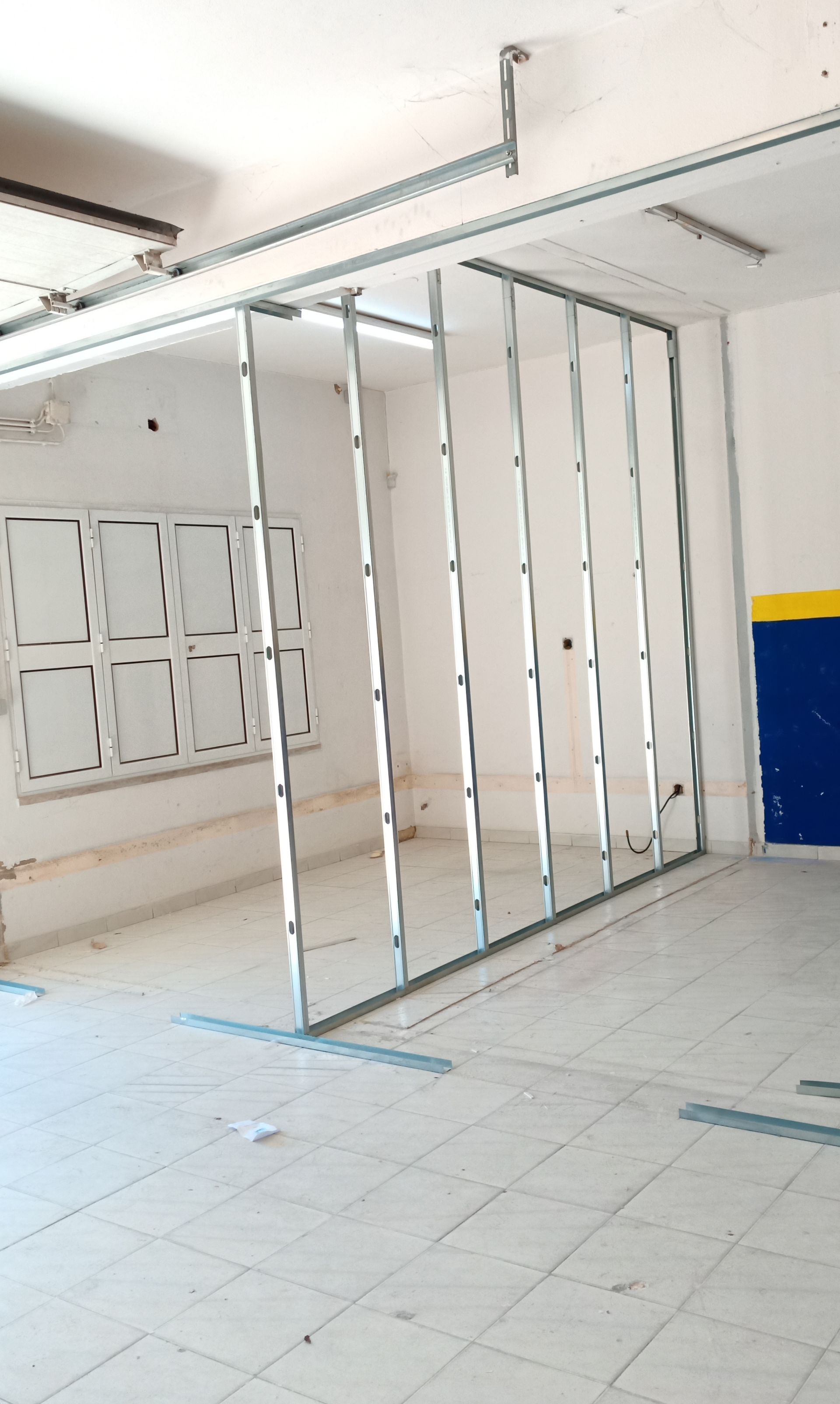 Estrutura metálica para parede de um cômodo, com janela e parede parcialmente pintada.