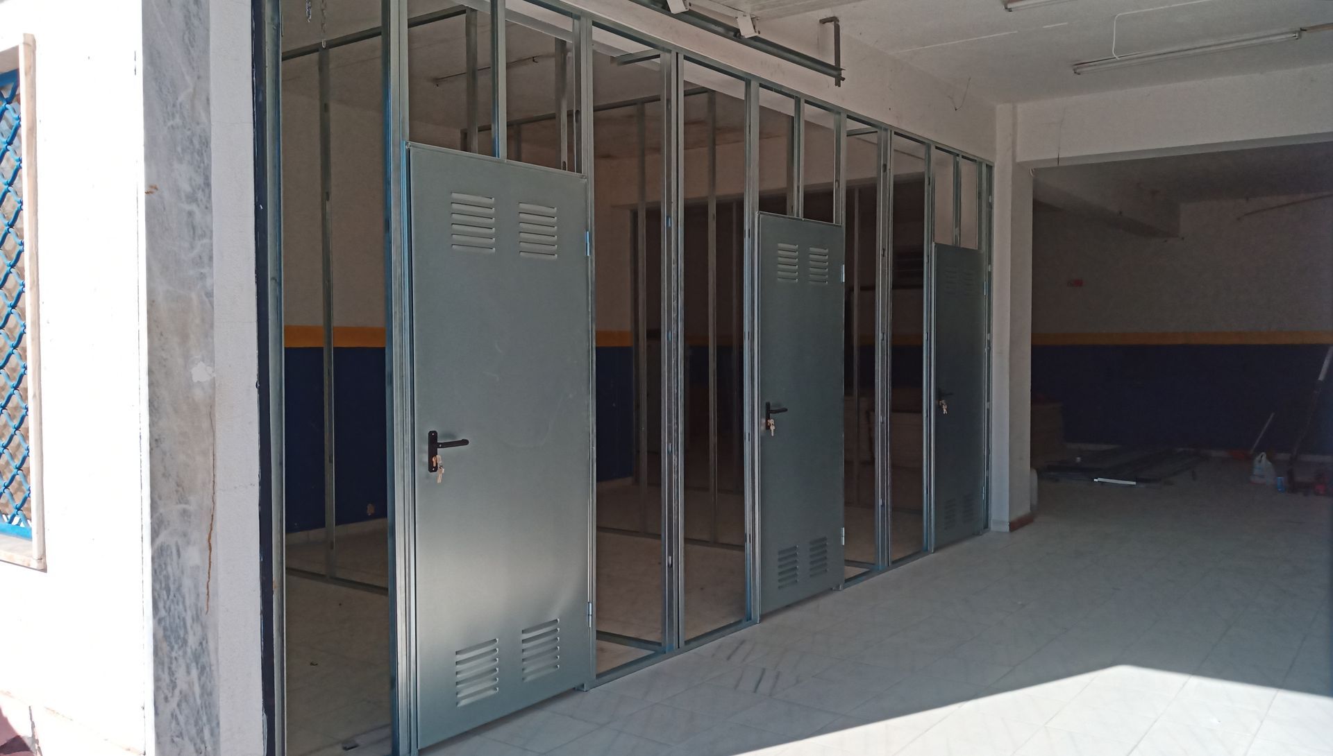 Portas de armário metálicas instaladas em uma parede estruturada em uma sala em construção.