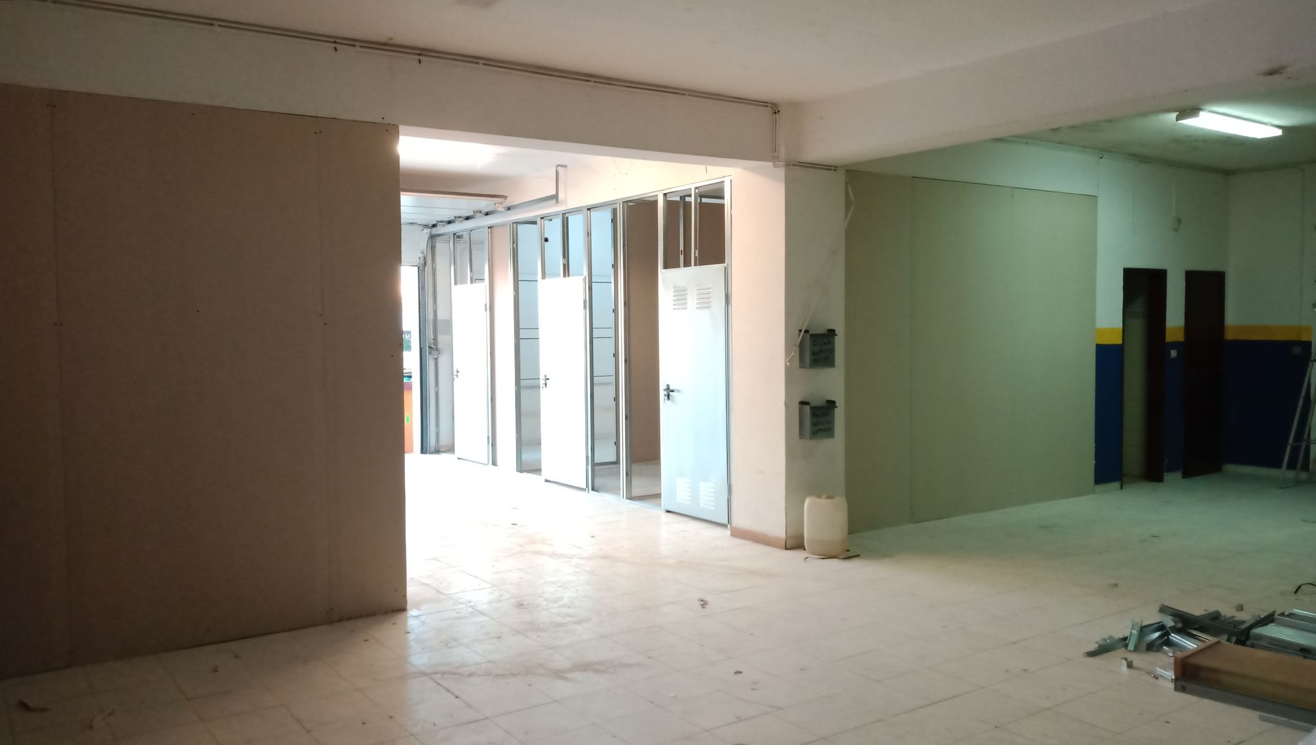 Construção interior em andamento; paredes parcialmente construídas, porta de entrada e piso inacabado.