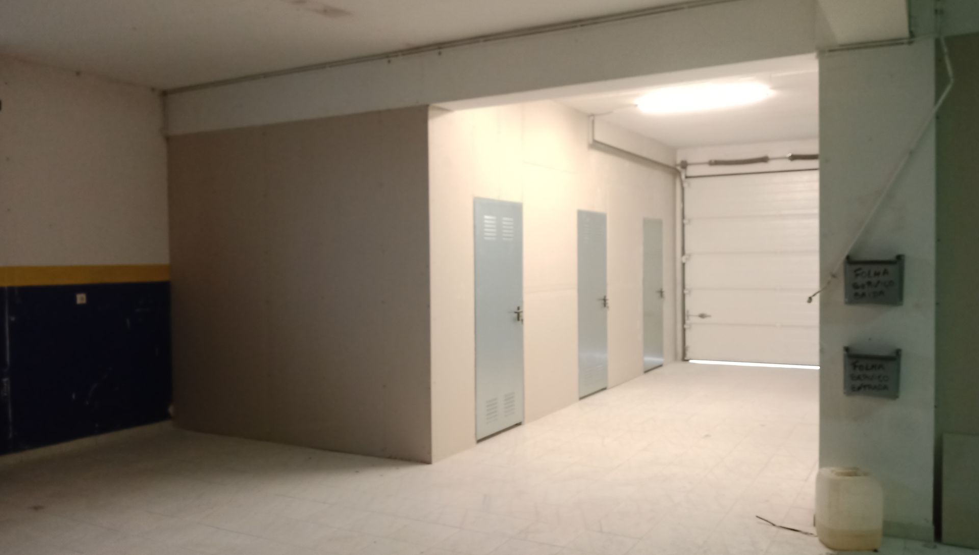 Um interior vazio com armários de armazenamento e uma porta de garagem. As paredes são de cores neutras.