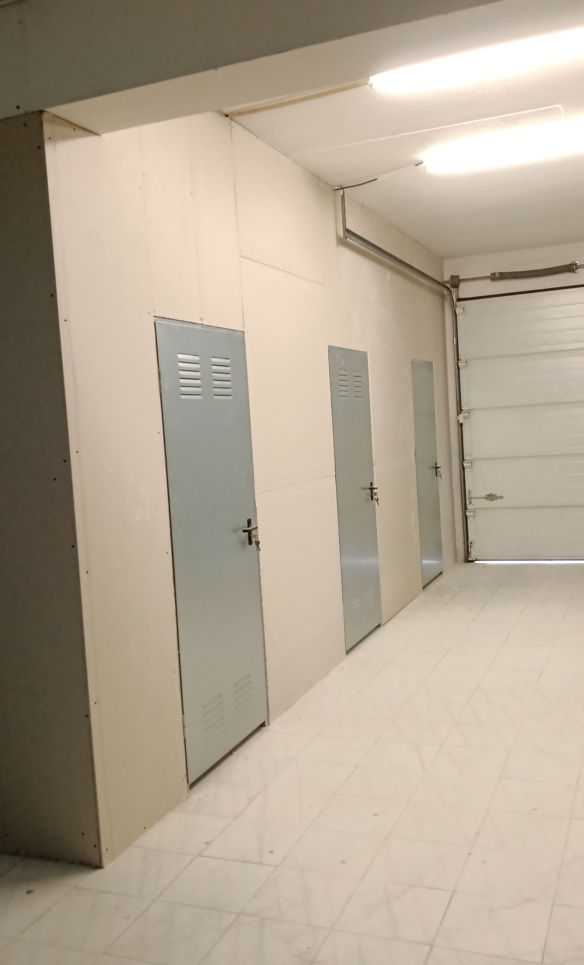 Corredor com três portas de armário e uma porta de enrolar.