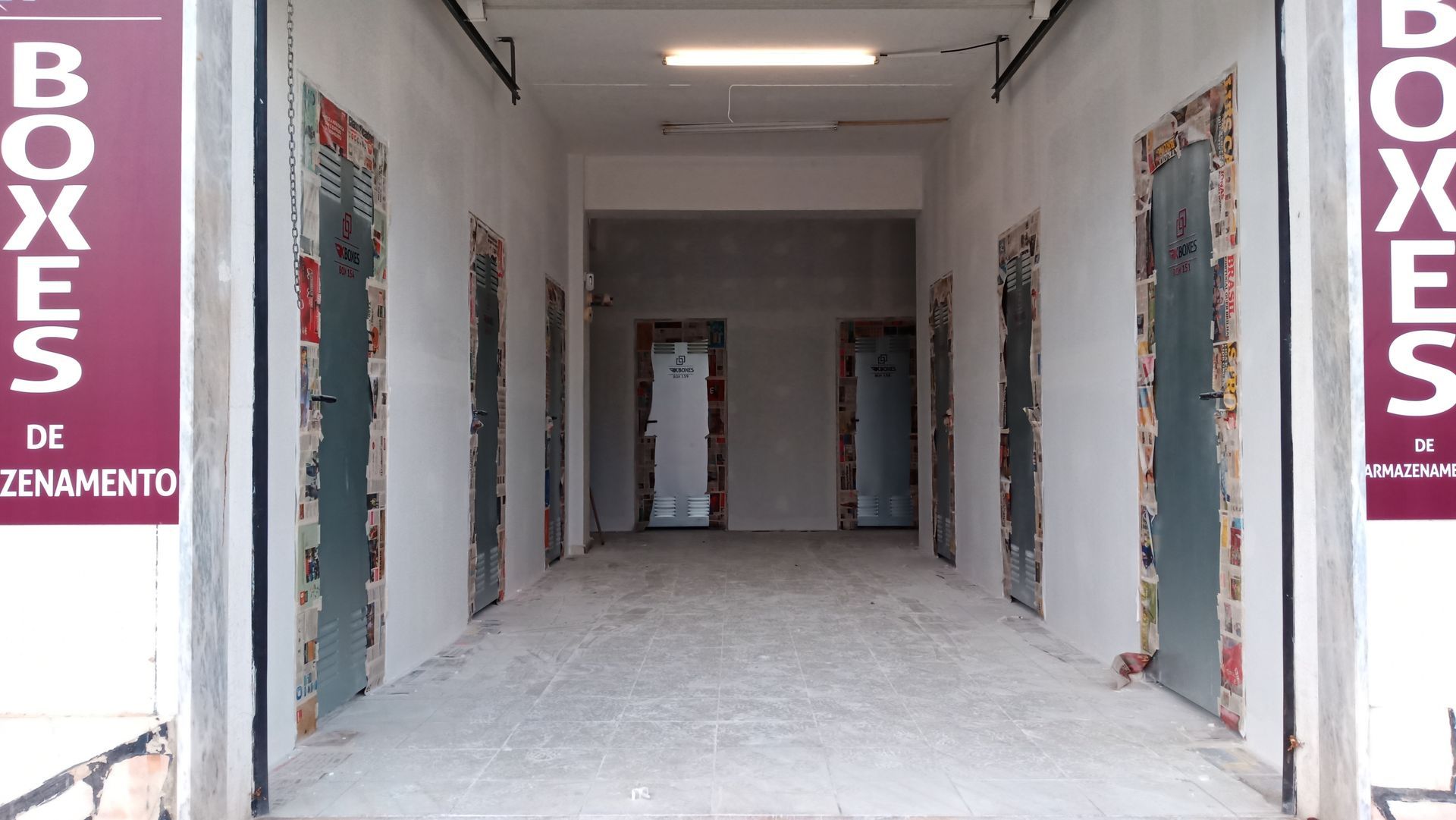 Um corredor com várias portas abertas, provavelmente depósitos. Placa com a palavra 