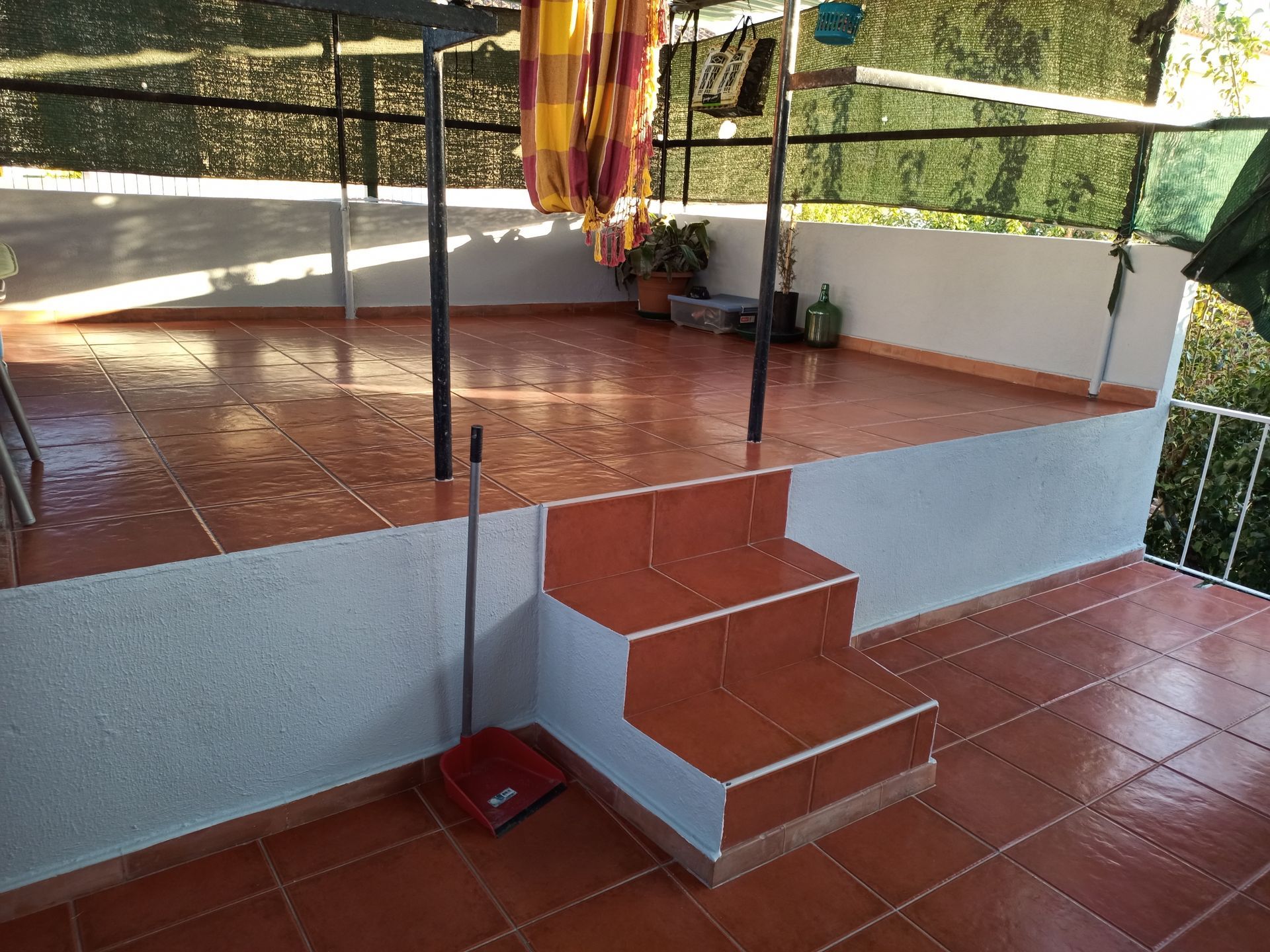 Pátio com degraus revestidos de azulejos. Uma cobertura escura proporciona sombra.