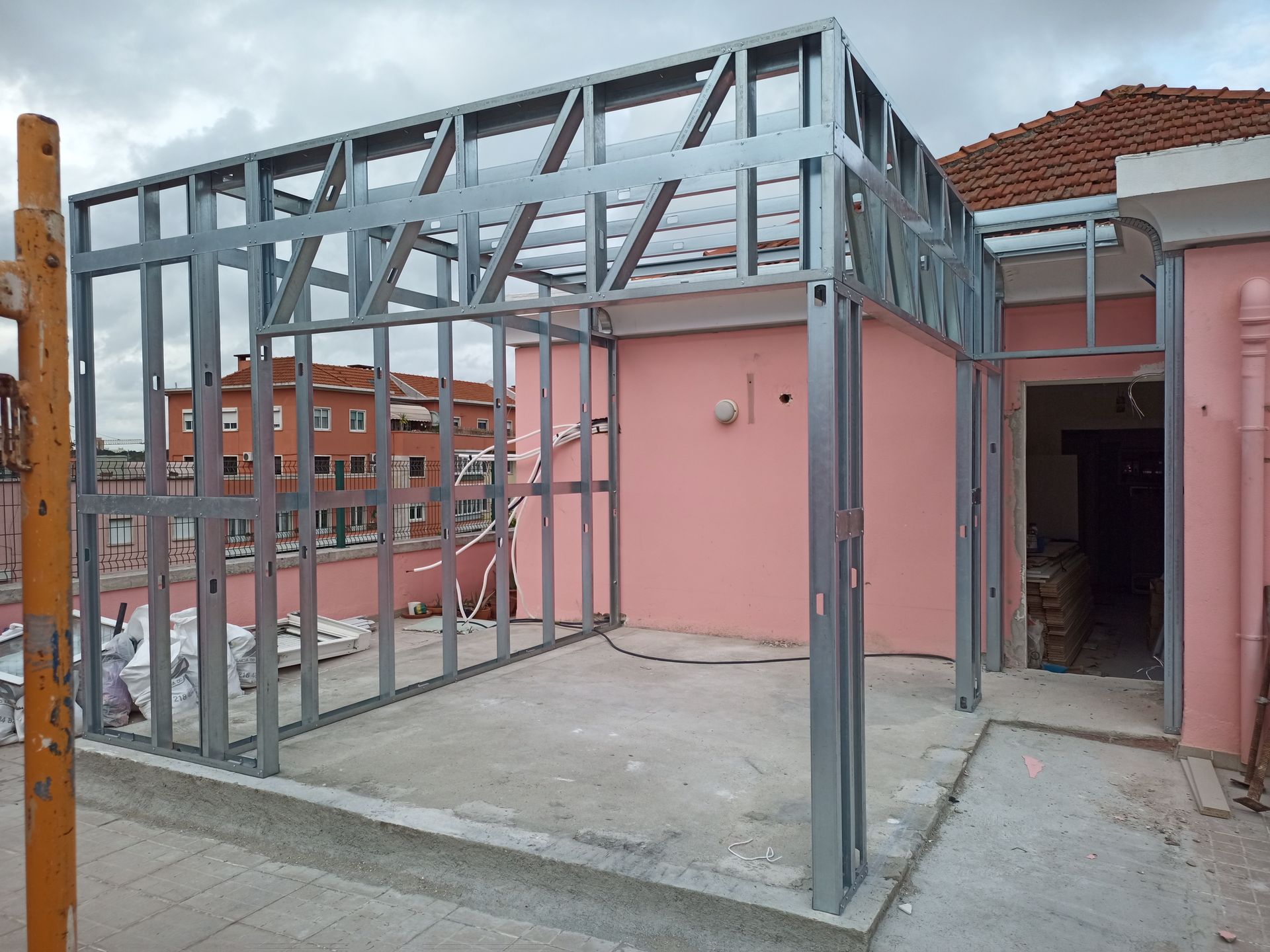 Estrutura metálica para ampliação de um prédio rosa.