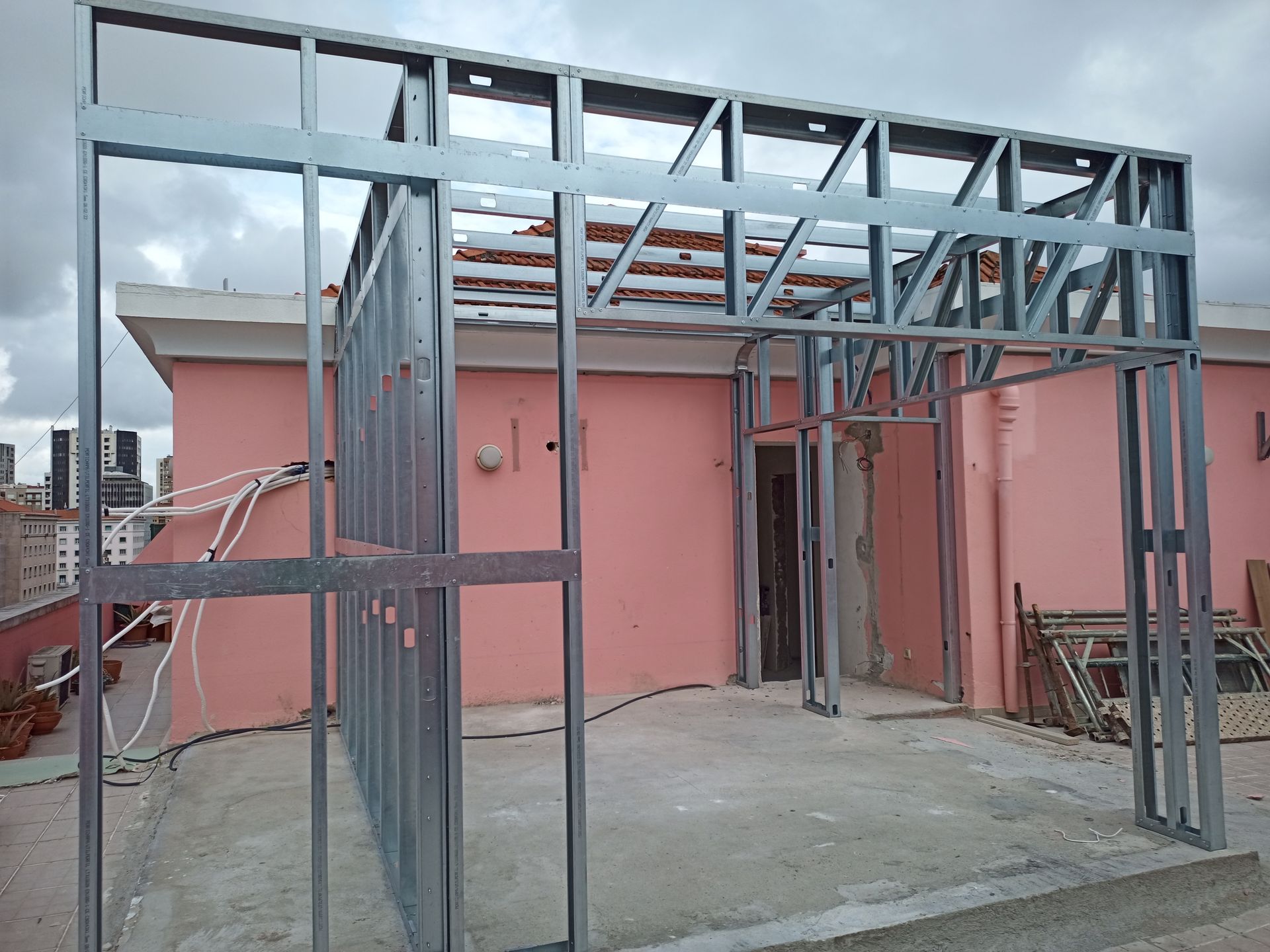 Estrutura de aço para cobertura, tendo como pano de fundo um prédio rosa.