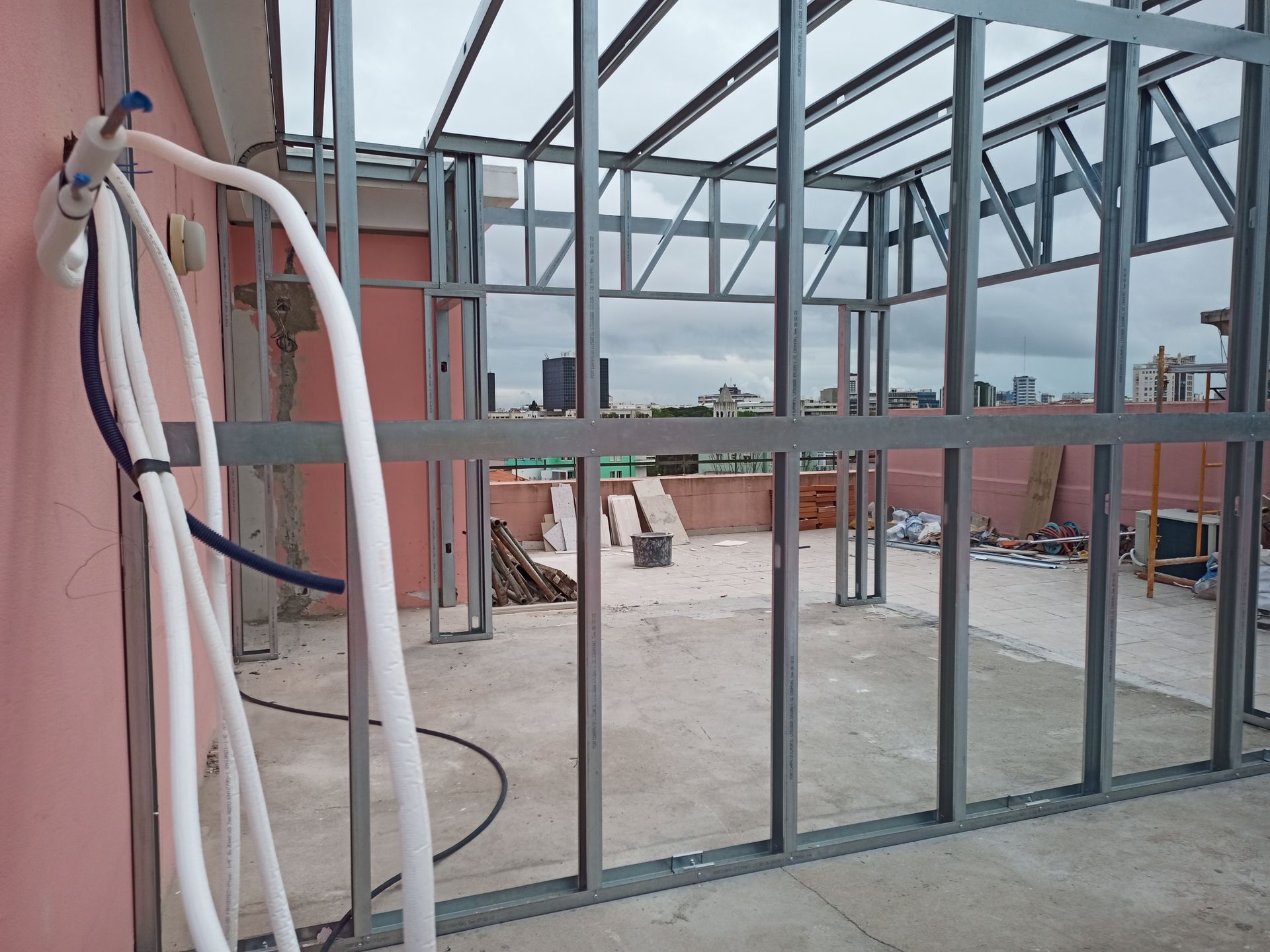Estrutura metálica para um edifício em construção num telhado, com o céu visível através da estrutura.
