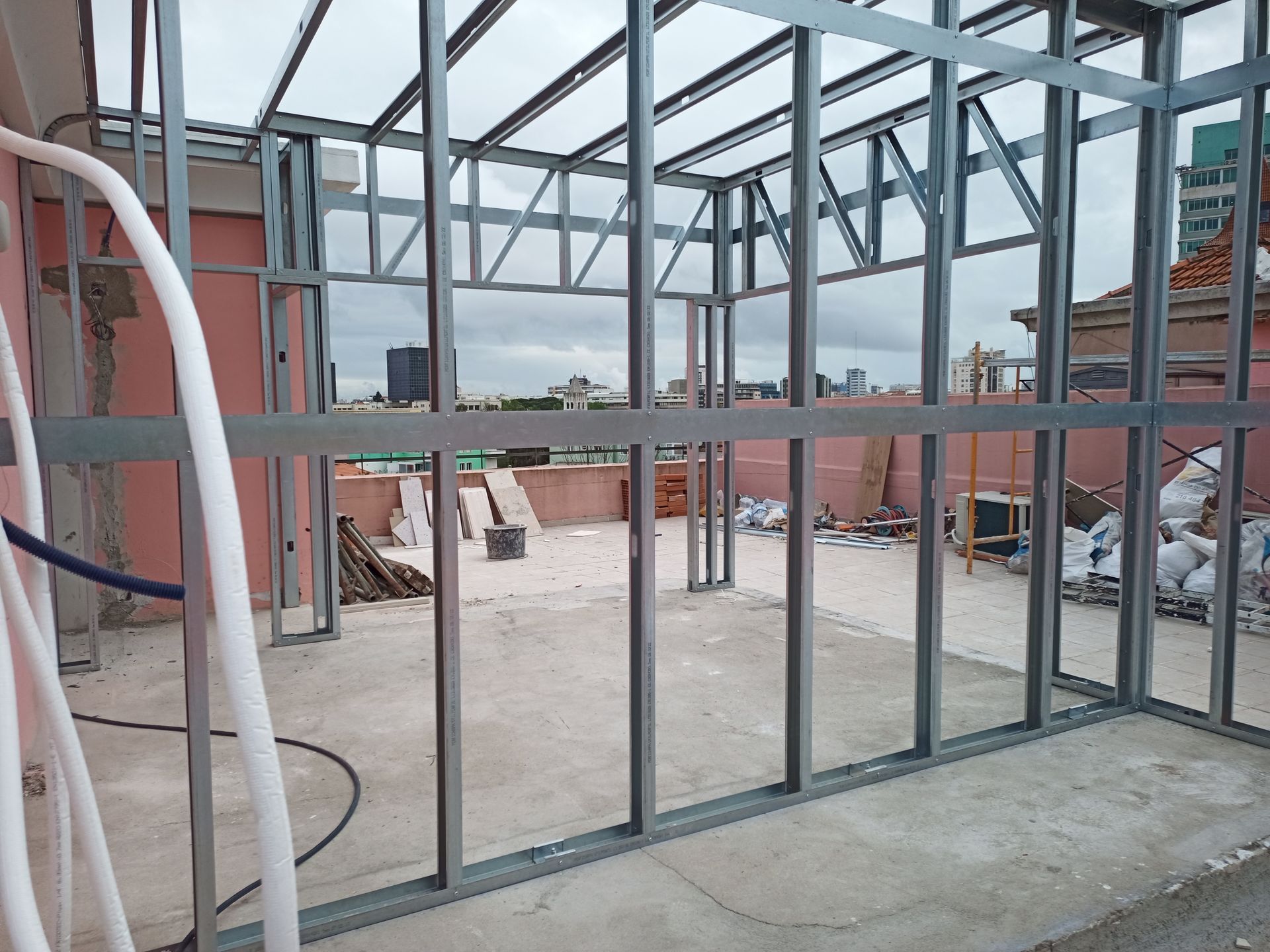 Estrutura metálica para o interior de um edifício em um terraço, com o horizonte da cidade visível ao fundo.