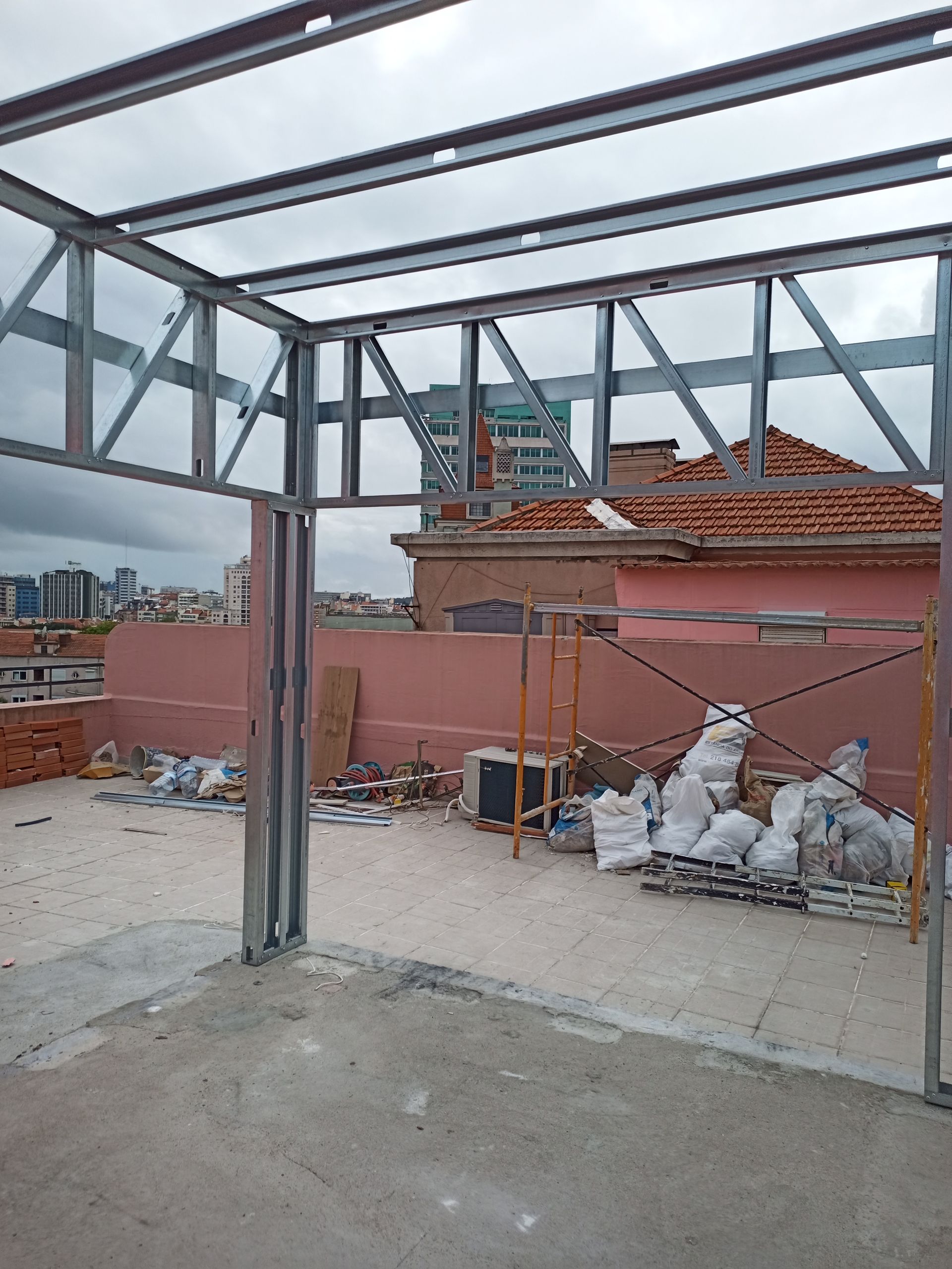 Estrutura de aço em construção em um telhado, com a cidade ao fundo.