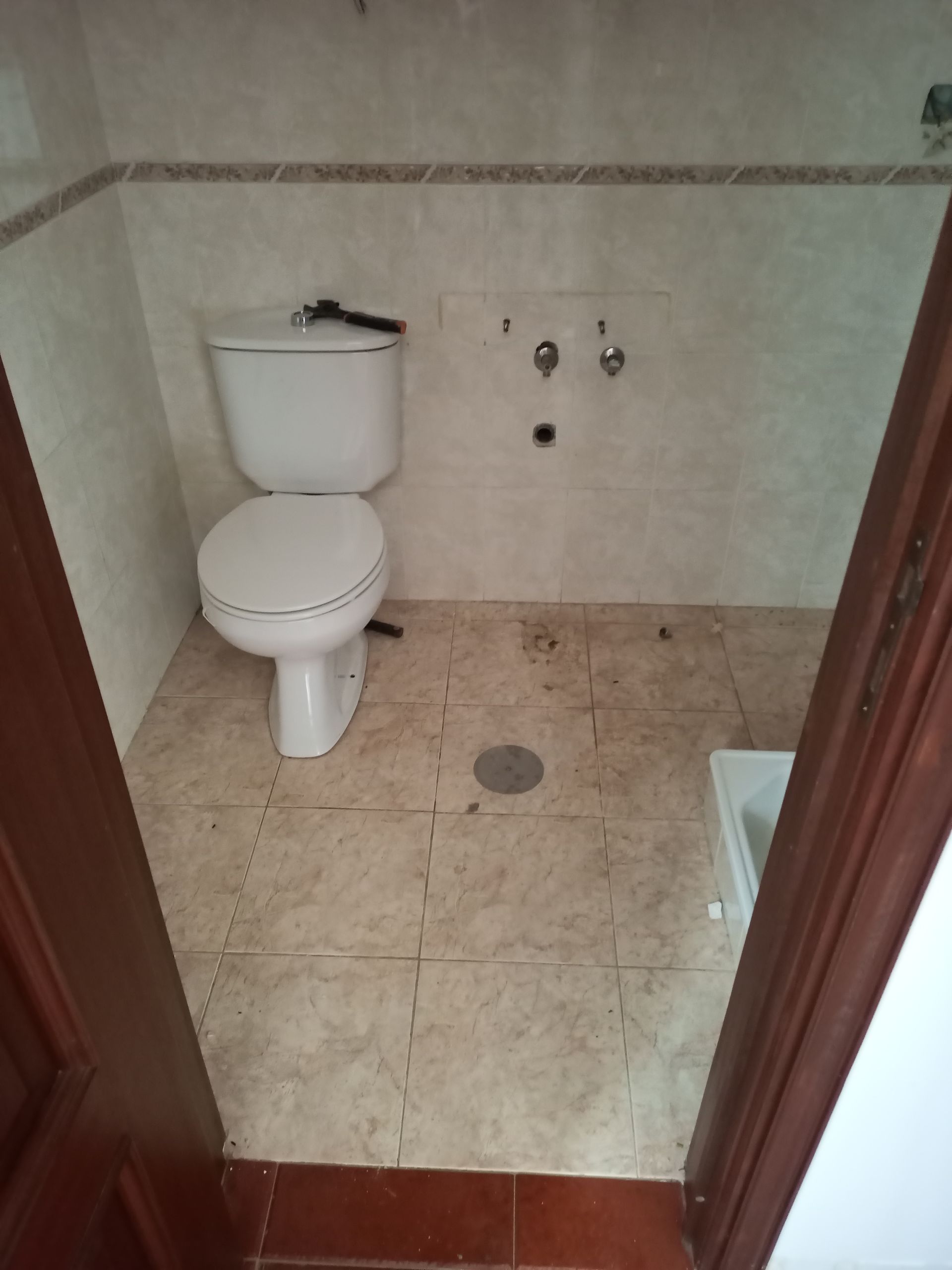 Um banheiro pequeno com vaso sanitário branco, paredes revestidas com azulejos e piso de azulejo.