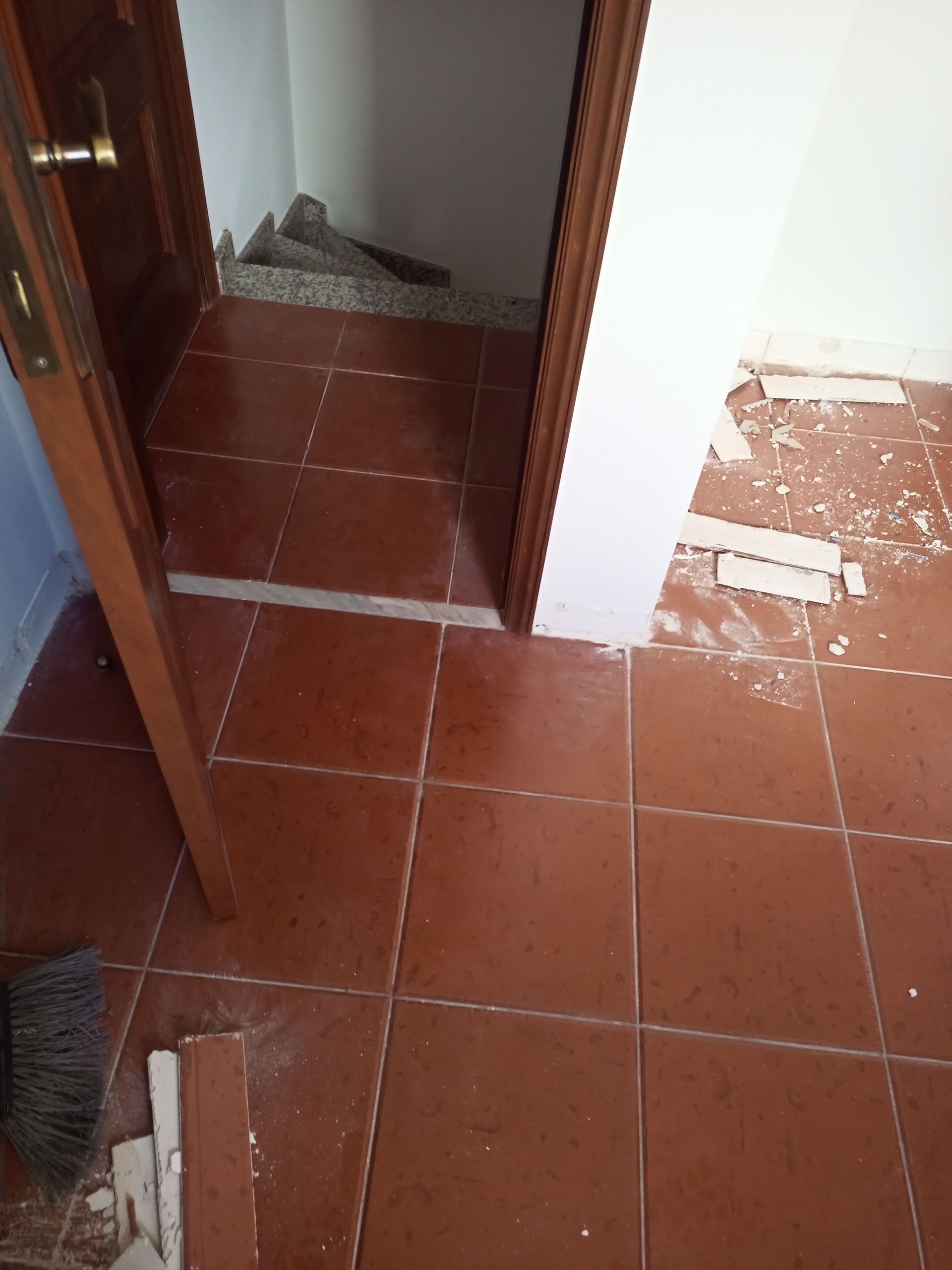 Piso de ladrilho vermelho com entrada, entulho e batente de porta.