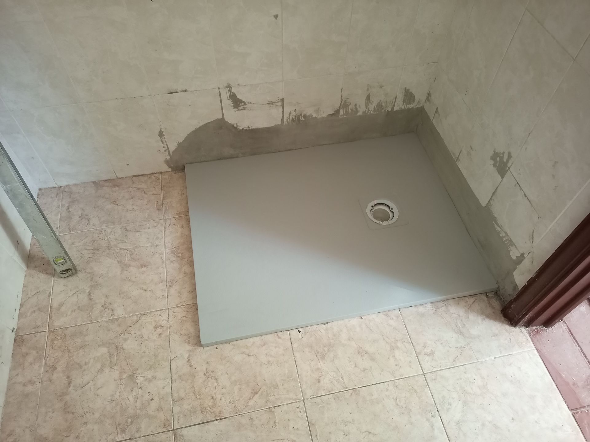 Base de chuveiro cinza instalada em banheiro revestido com azulejos.