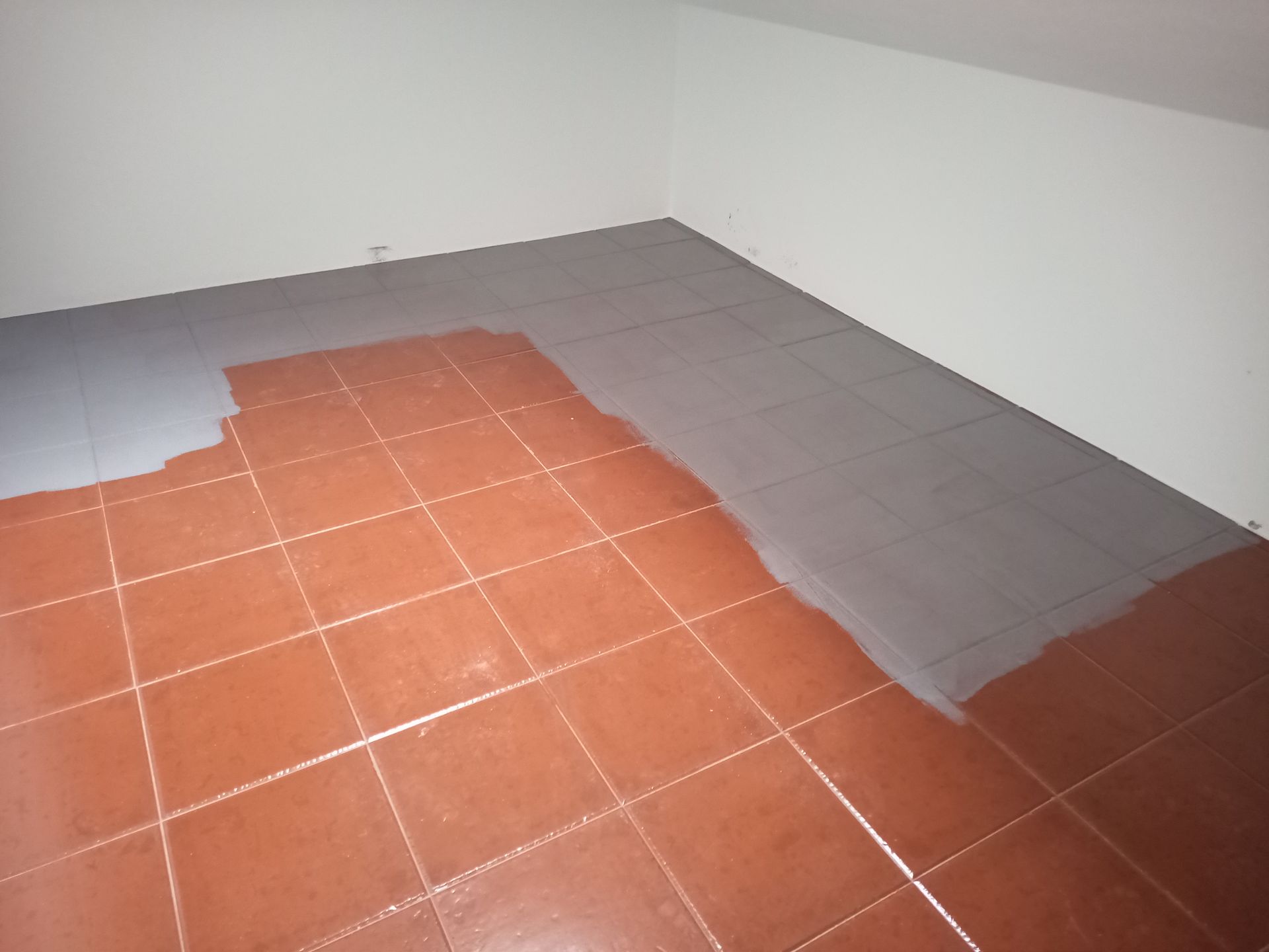 Pisos de cerâmica pintados de cinza em um cômodo com paredes brancas.