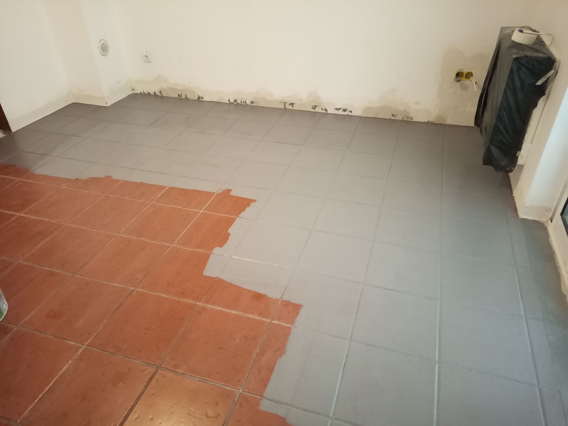 Tinta cinza aplicada sobre ladrilhos de terracota no piso, cobrindo parcialmente a cor original.