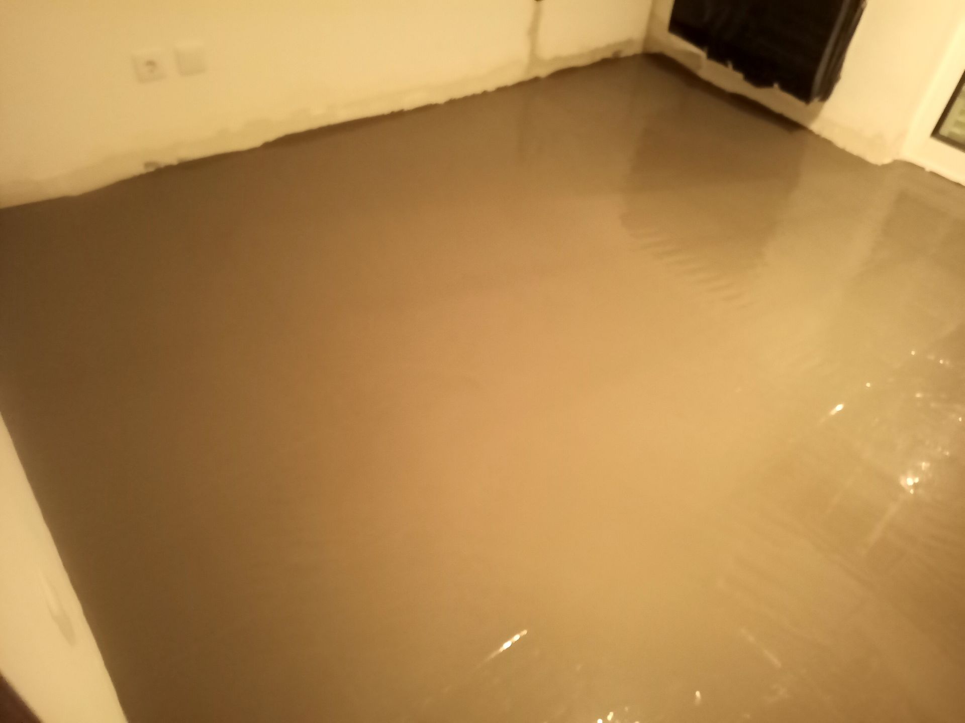 Piso de concreto recém-moldado, liso e úmido, em um cômodo.
