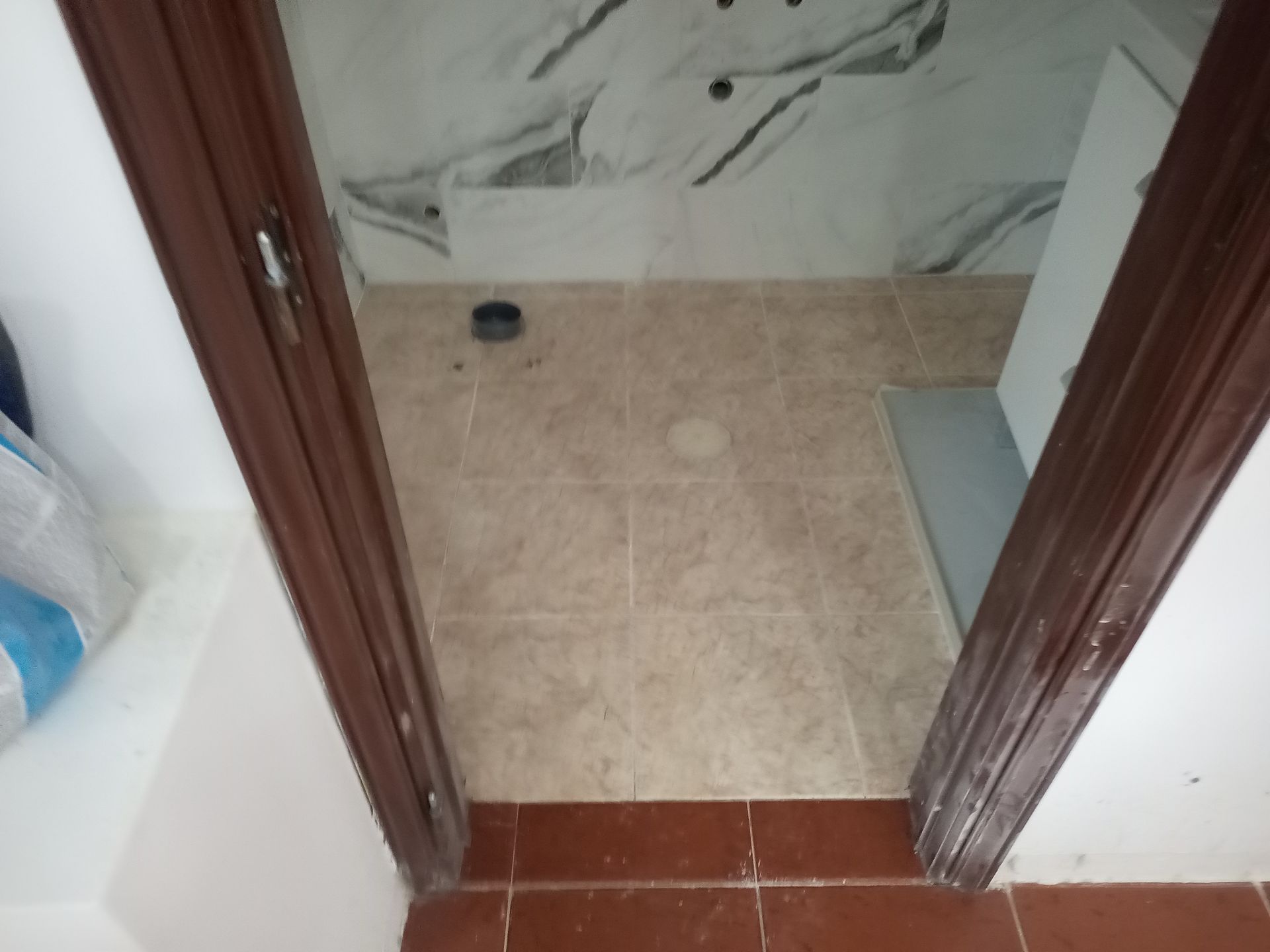 Porta do banheiro com piso de azulejo marrom e batente marrom.