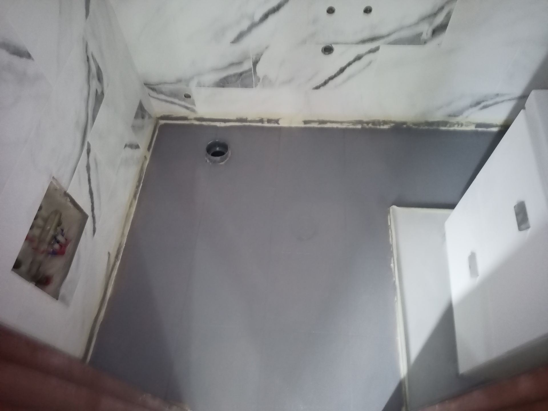 Interior de banheiro com paredes cinza e teto de mármore. Um armário branco está à direita.