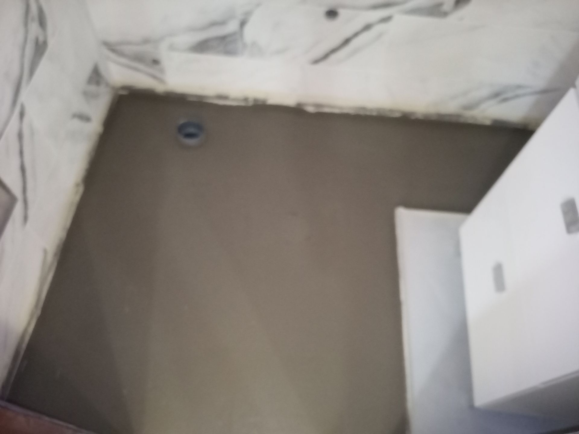 Piso do banheiro com argamassa cinza fresca, ralo visível, paredes inacabadas.