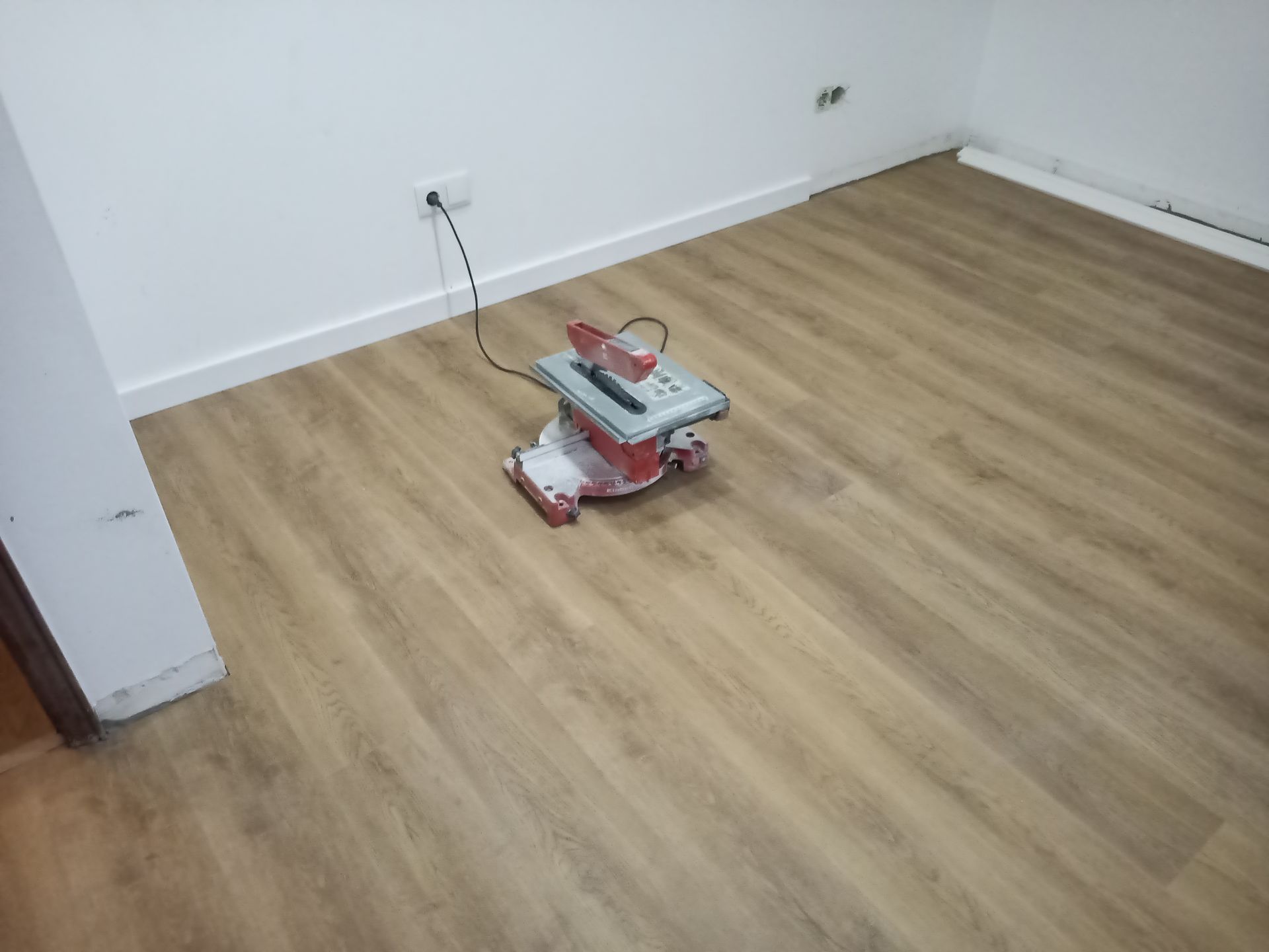 Serra de esquadria em piso laminado com aparência de madeira instalado em um cômodo com paredes e rodapés brancos.