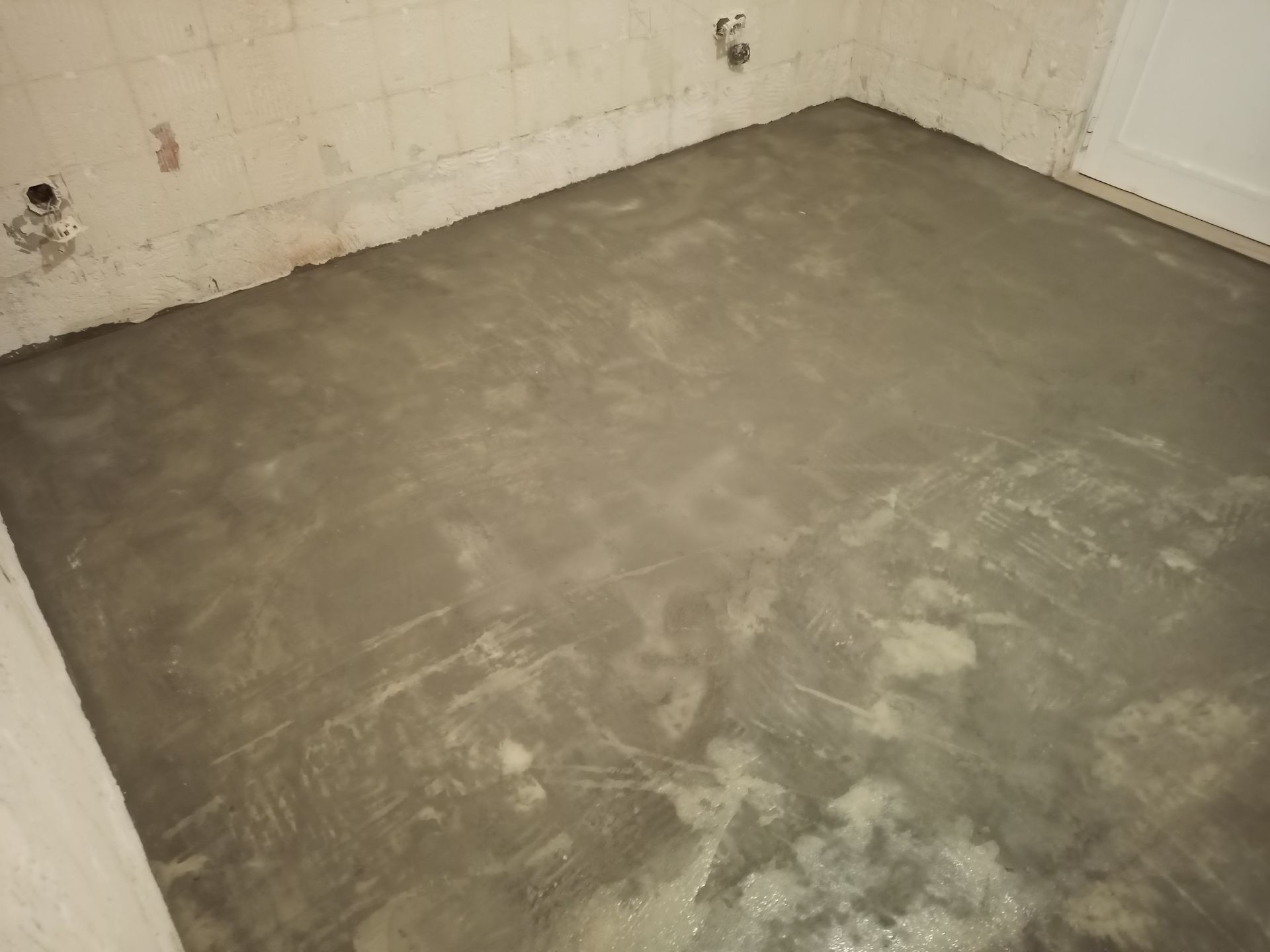 Piso de concreto recém-instalado em um cômodo, com as paredes visíveis.