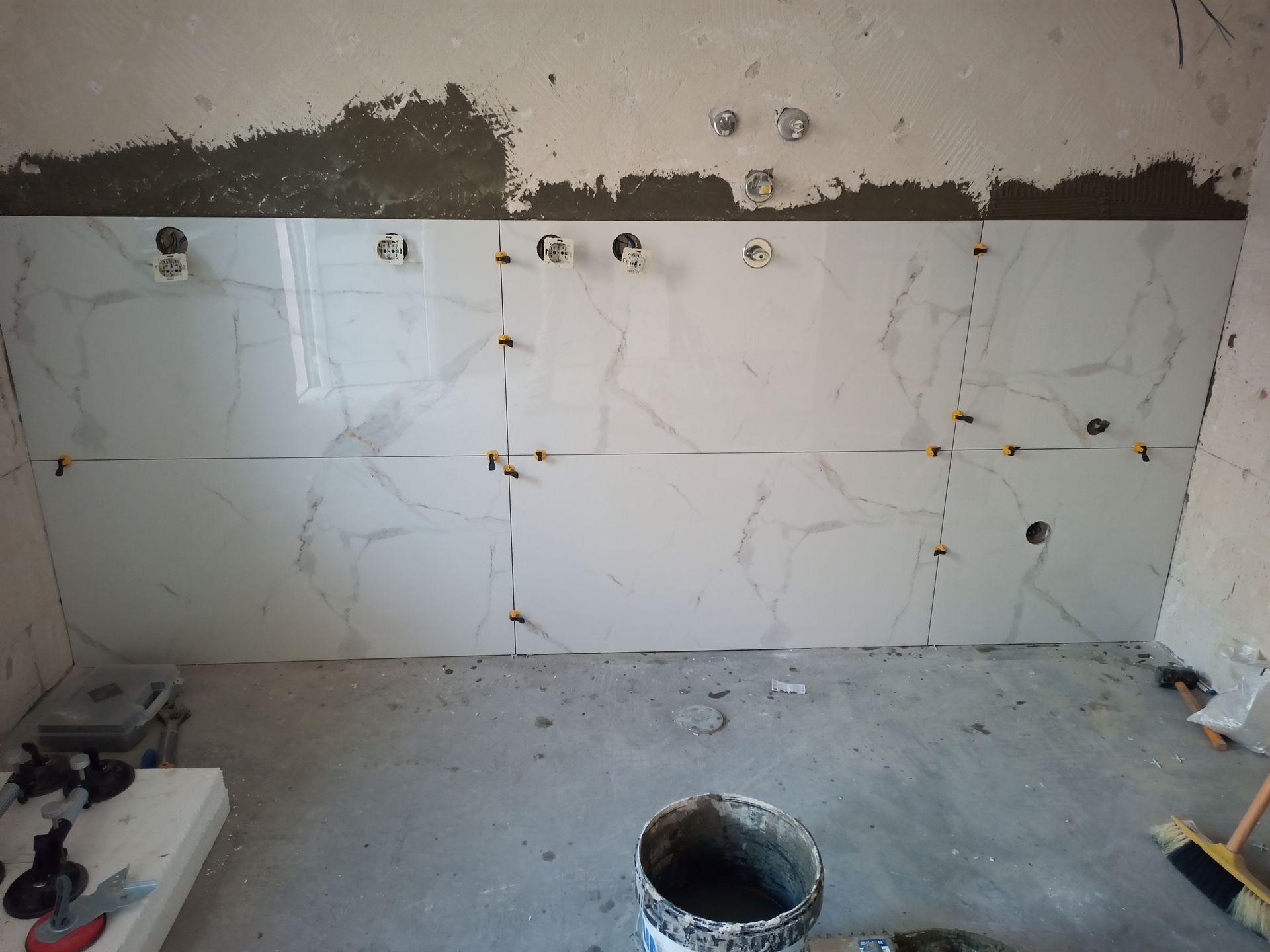 Azulejos de mármore branco instalados em uma parede, construção em andamento.