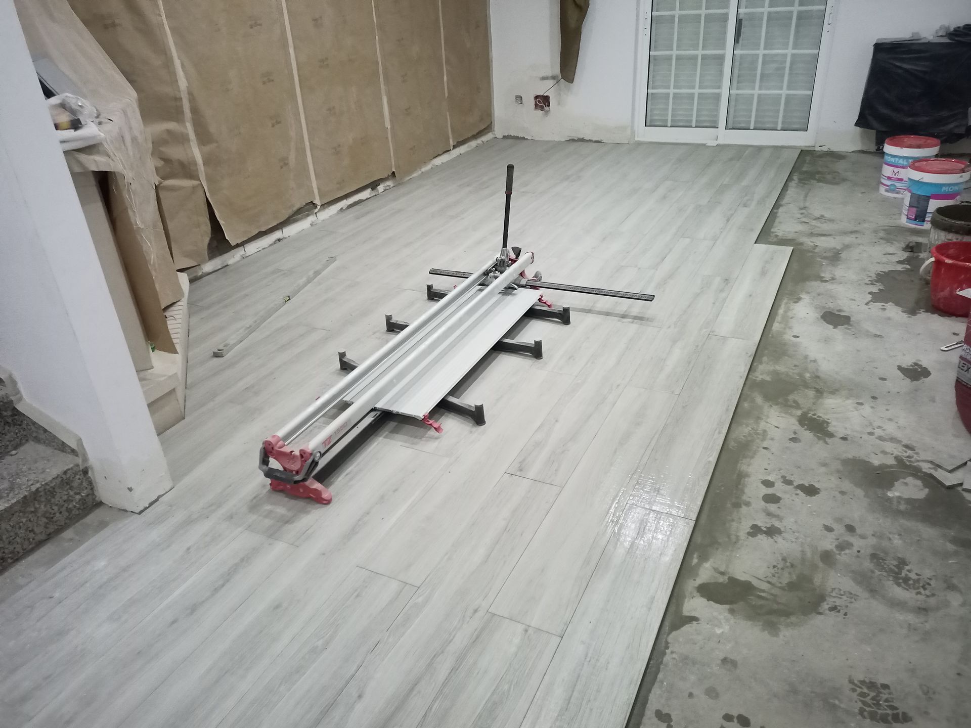 Cortador de azulejos sobre azulejos cinzentos instalados em uma sala.