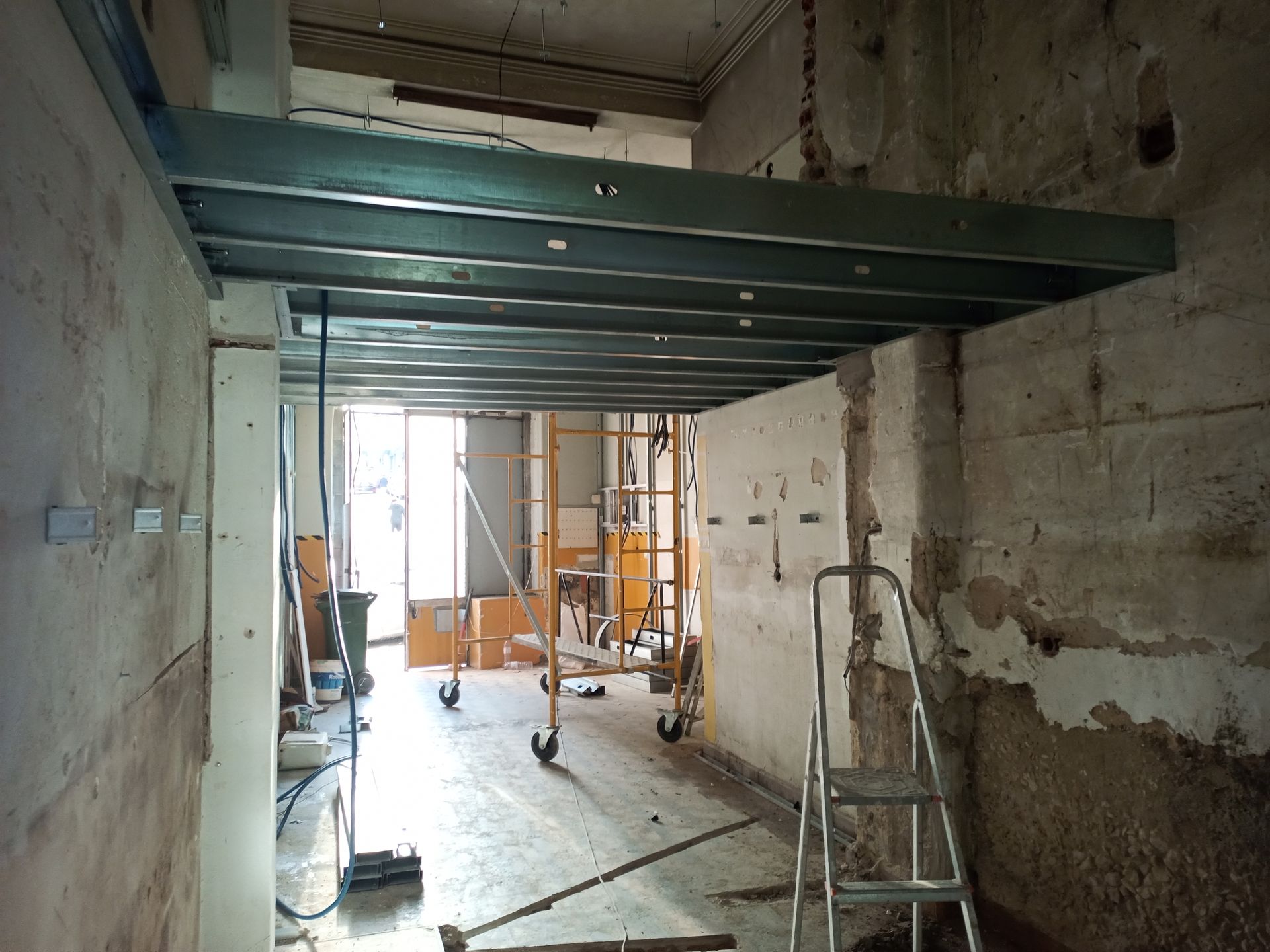 Canteiro de obras: estrutura metálica instalada em um cômodo estreito com paredes e ferramentas expostas.