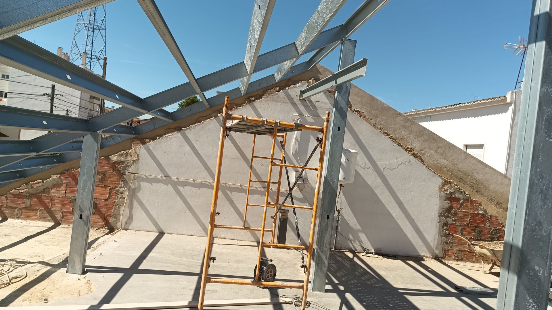 Estrutura metálica com escada encostada em um prédio sob um céu azul claro.