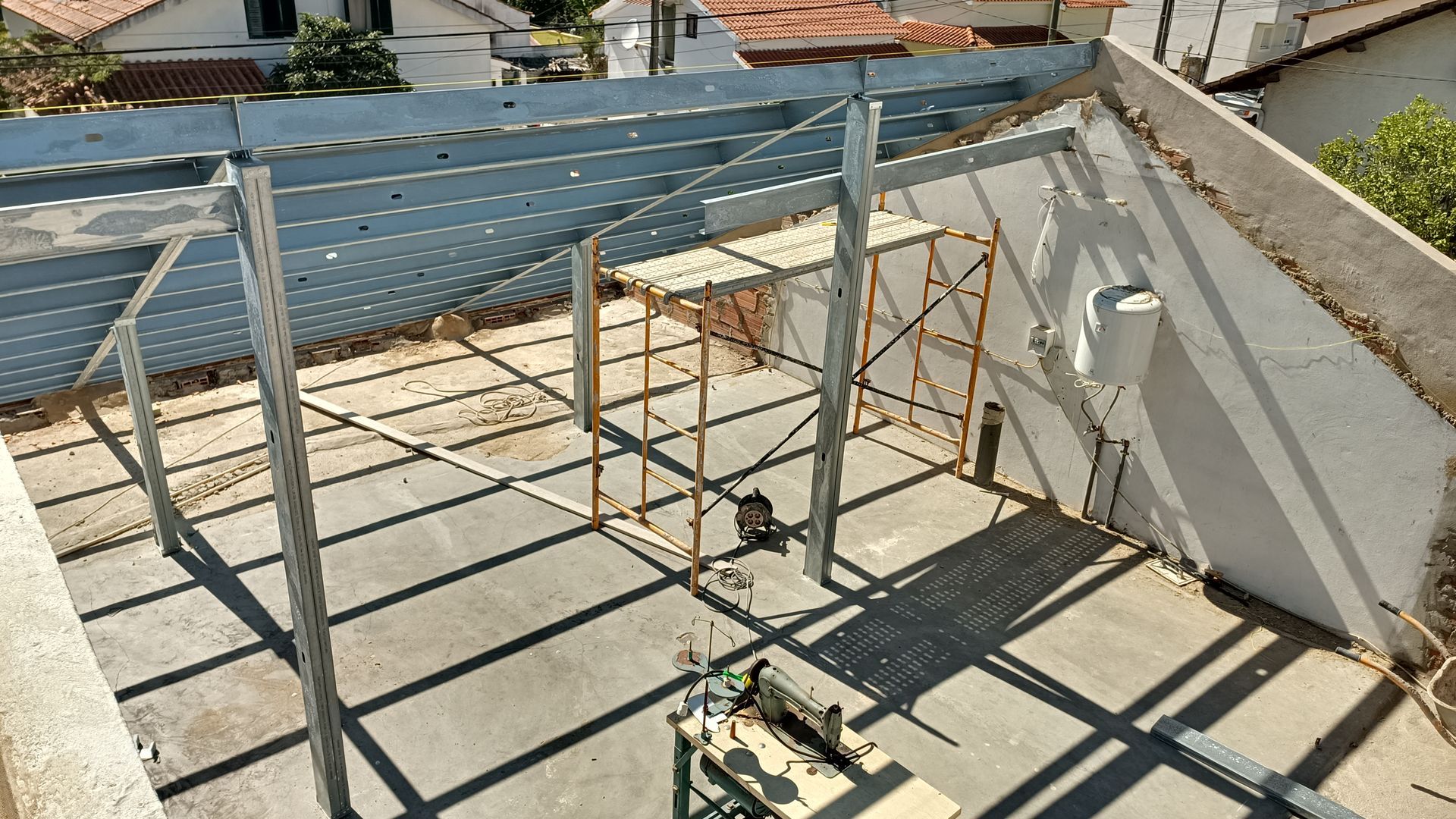 Estrutura metálica para uma construção com andaimes internos, sobre uma superfície de concreto.