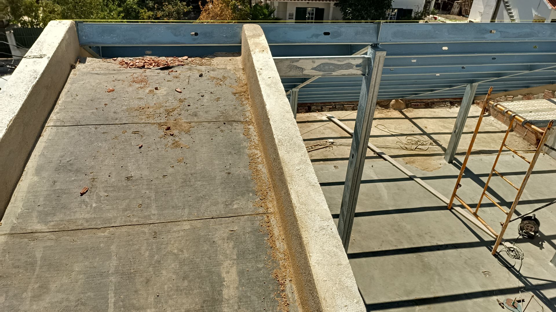 Canteiro de obras: laje de concreto para cobertura com estrutura metálica e bordas de concreto.