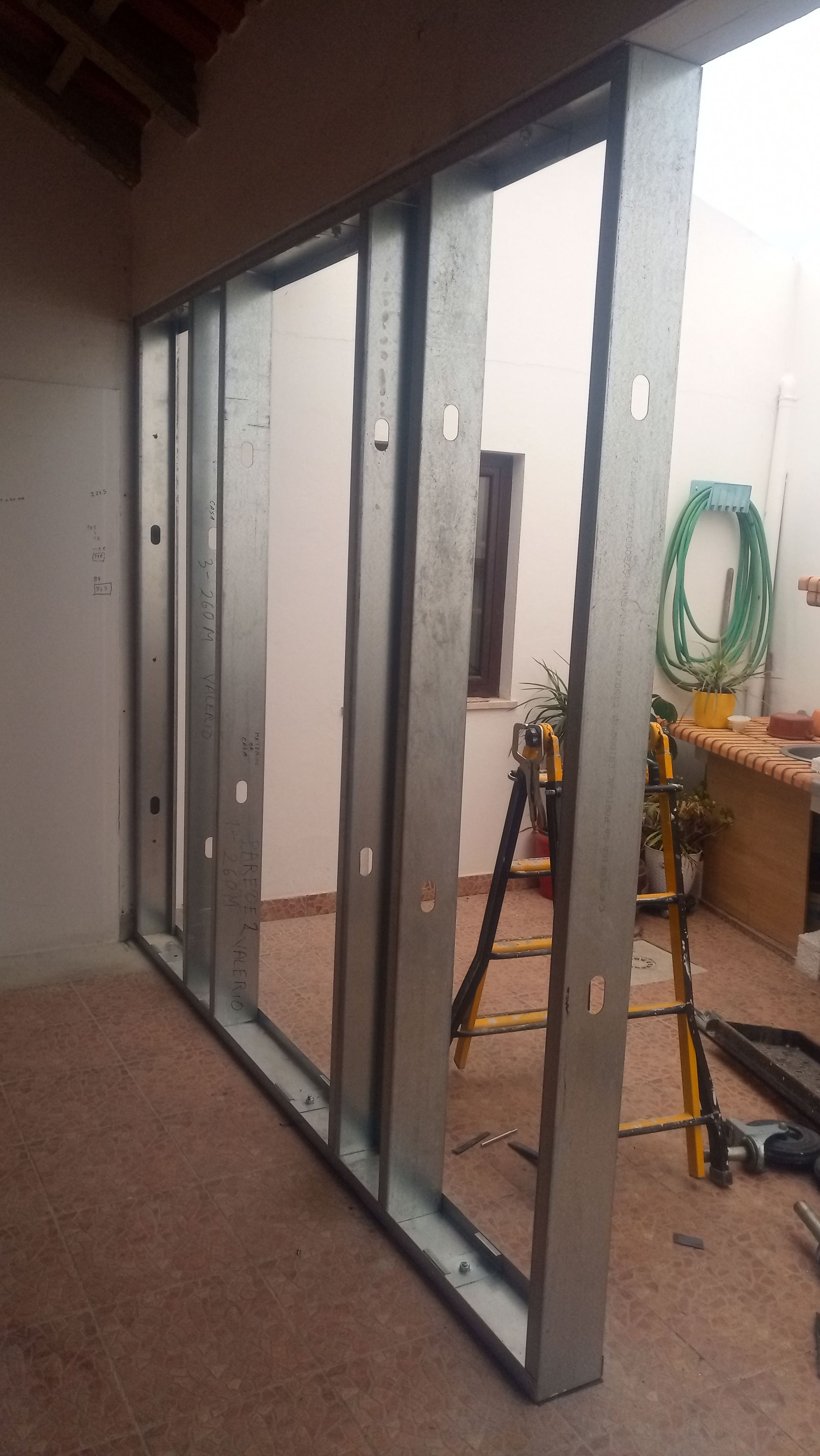 Estrutura metálica para parede, parcialmente construída em ambiente externo.