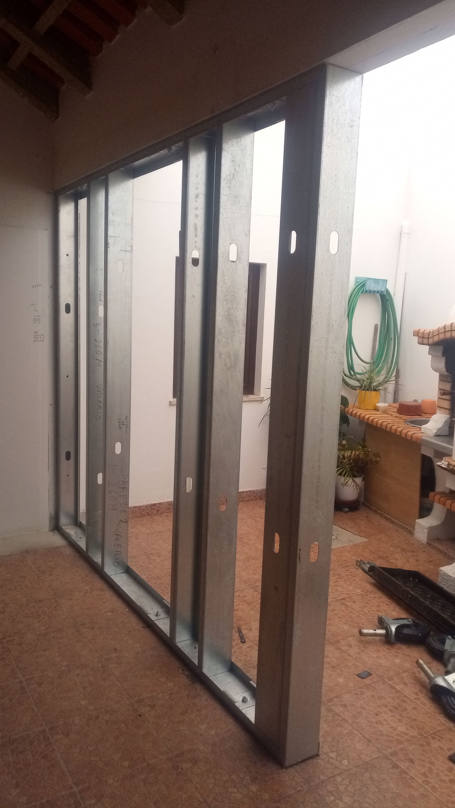 Estrutura metálica para uma parede em um prédio em construção, revelando um espaço aberto e um pátio.