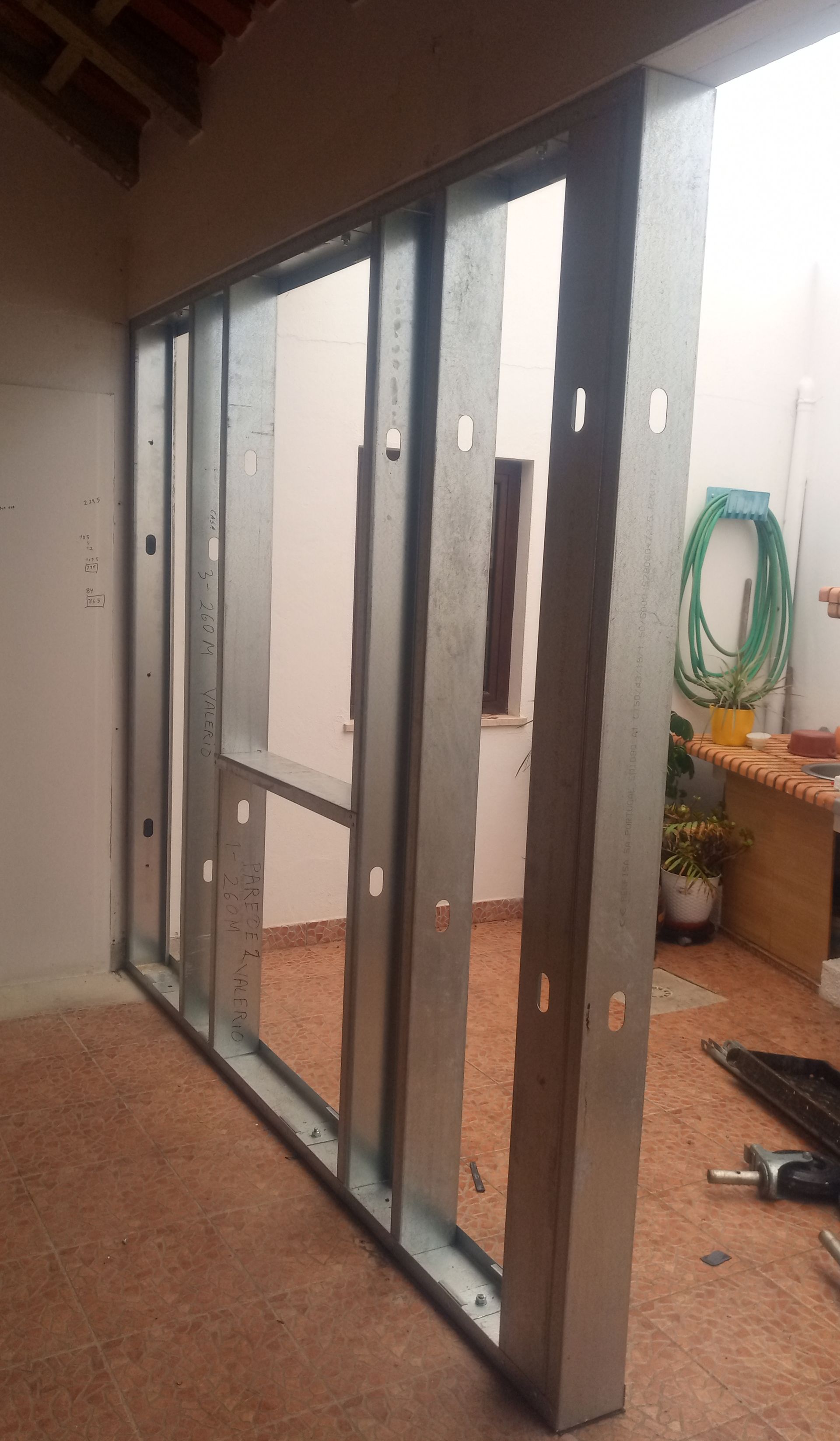 Estrutura de parede com montantes metálicos em construção, ao ar livre.