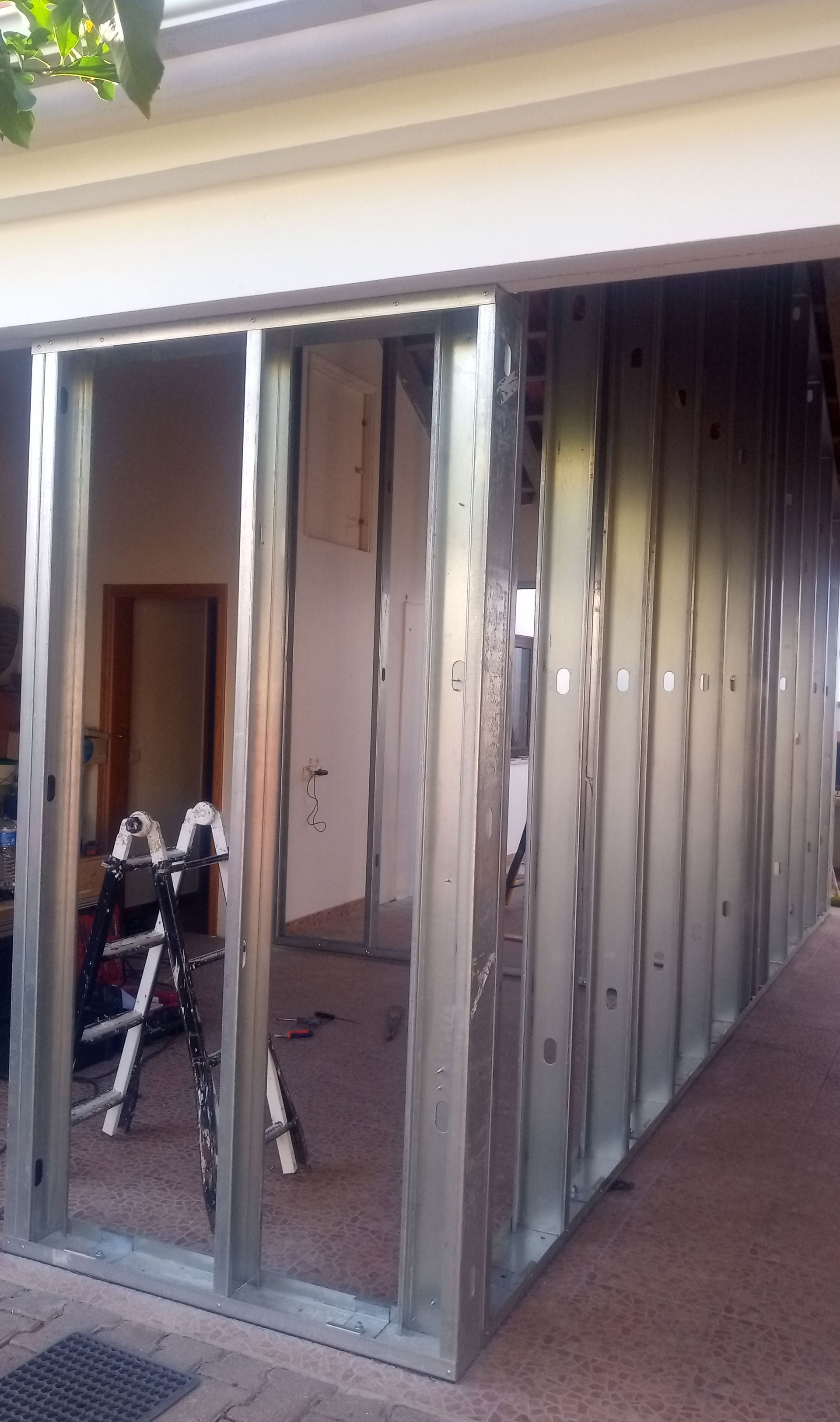 Estrutura metálica de uma parede, possivelmente para a construção de um cômodo adicional, sob a saliência do edifício.