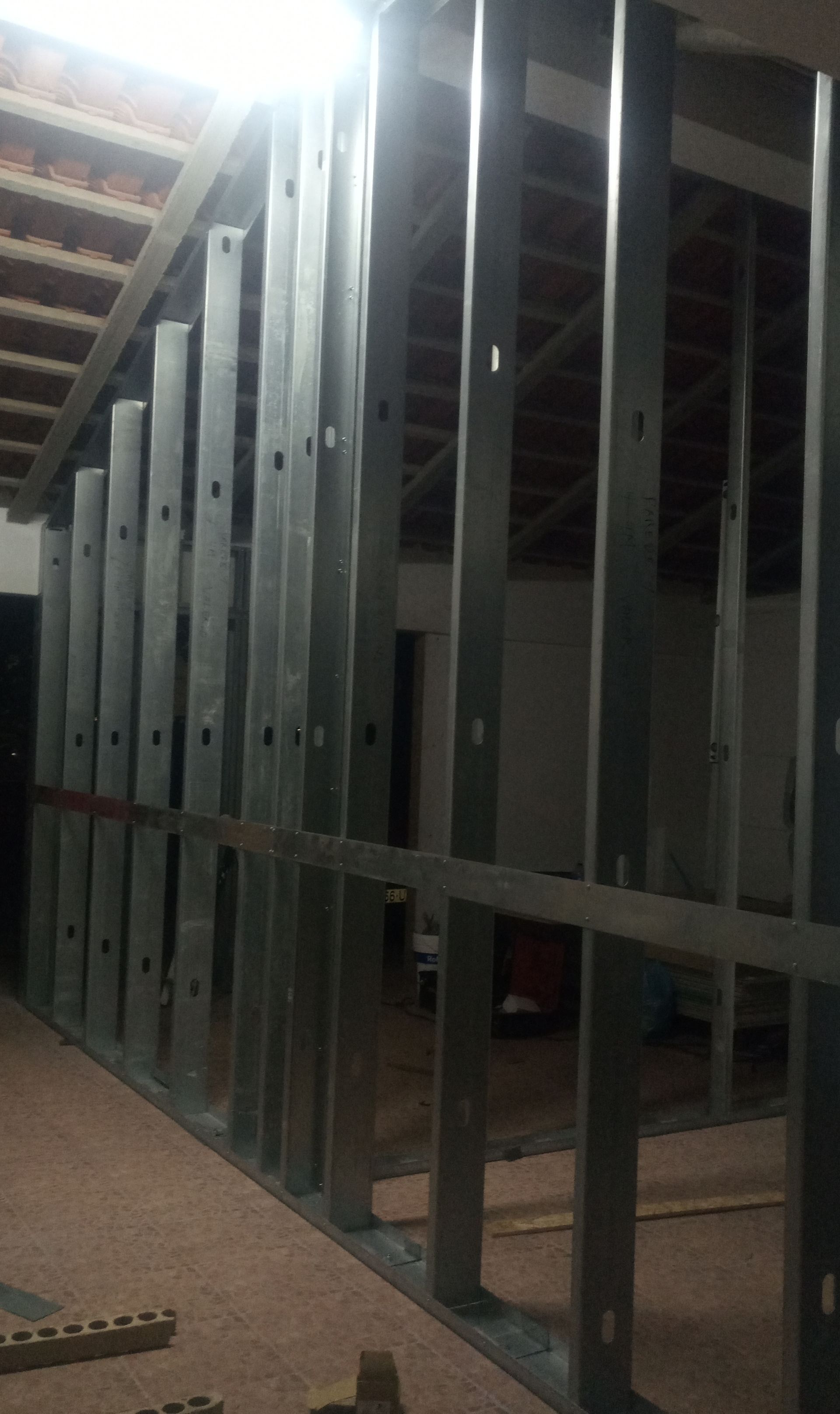 Perfis metálicos de uma estrutura de parede, em ambiente interno, durante a construção.