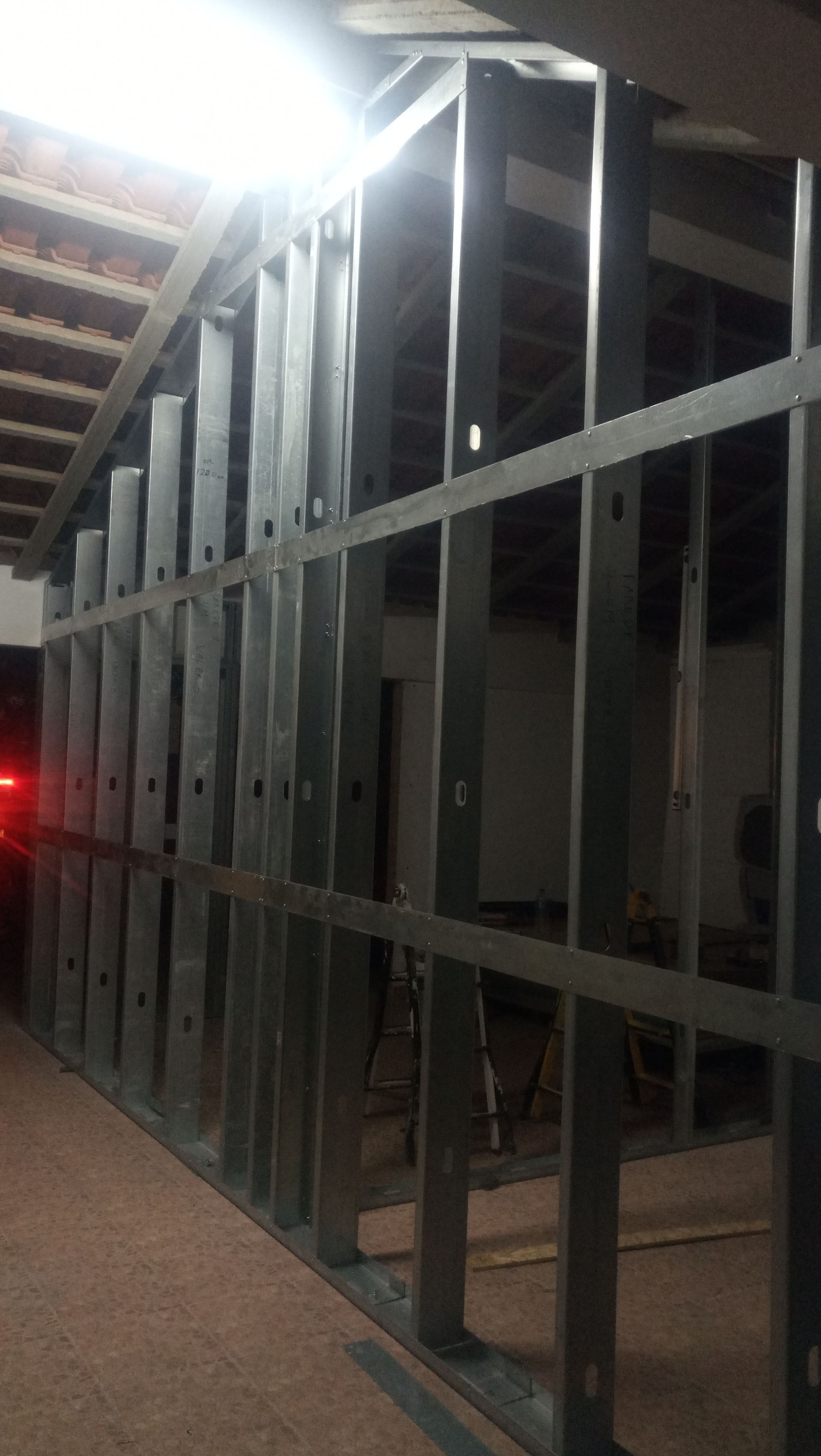 Perfis metálicos que formam a estrutura de uma parede dentro de um edifício em construção.