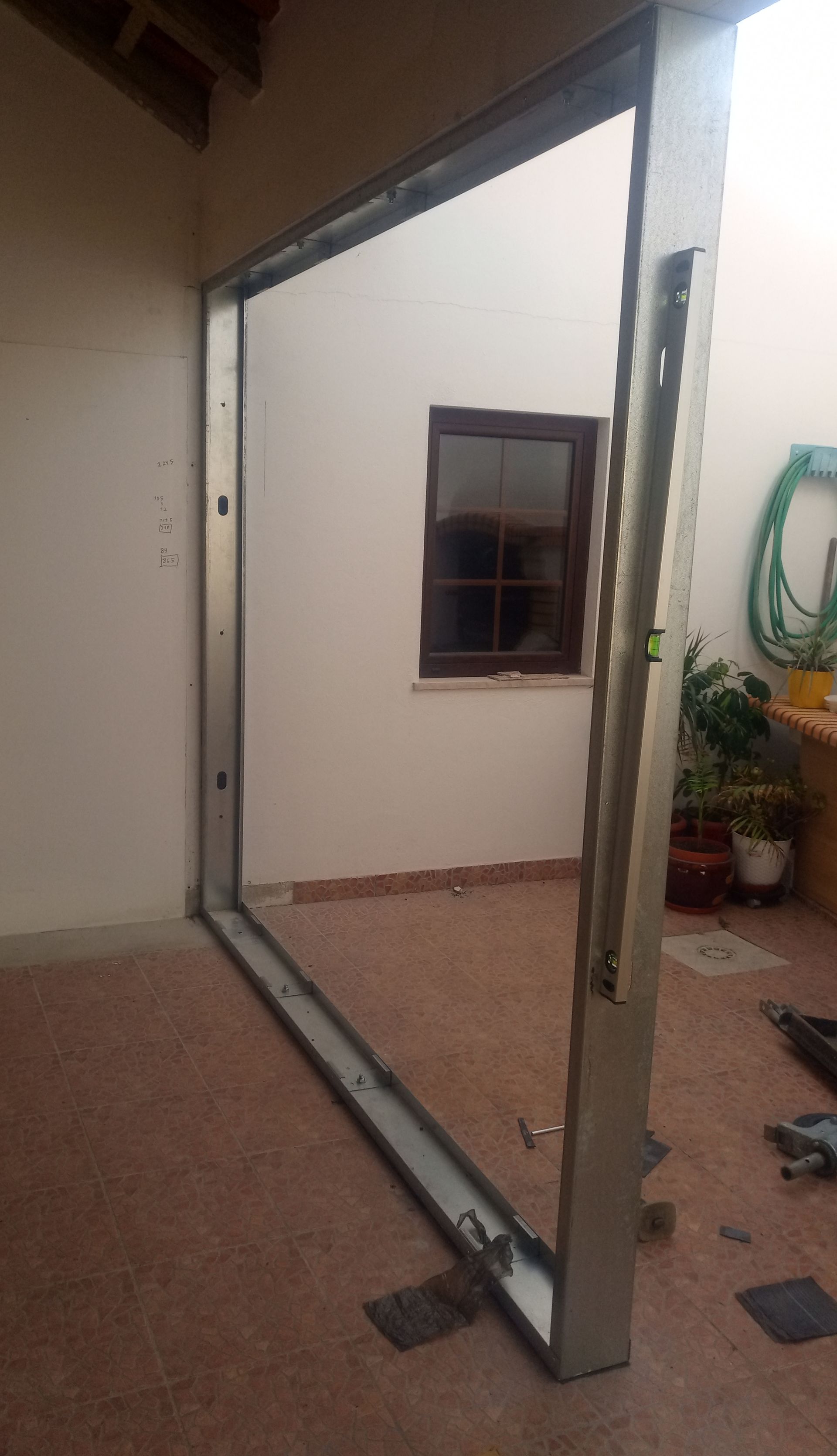 Caixilho de porta de alumínio vazio instalado em ambiente externo, com vista para uma janela.