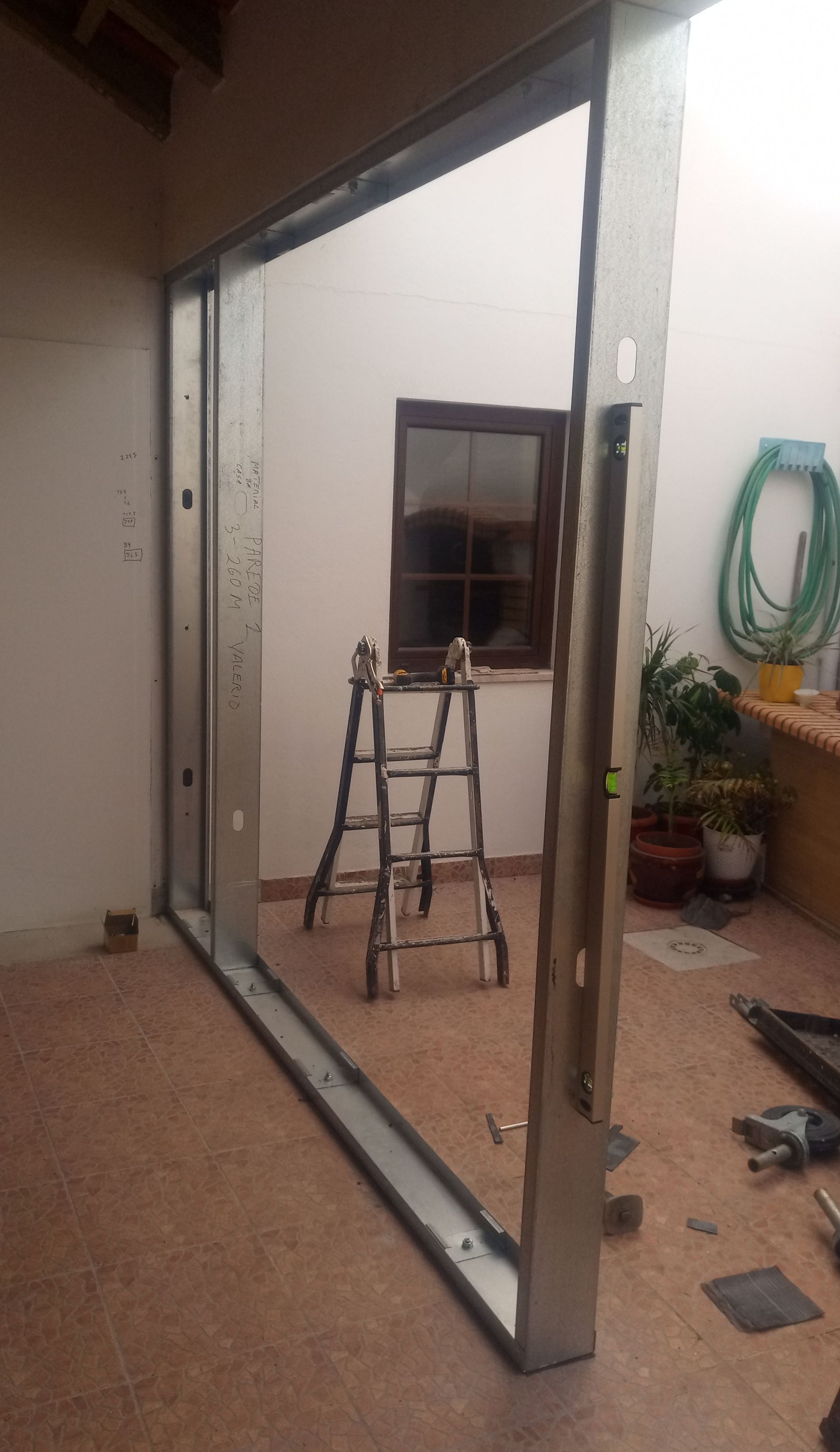 Batente de porta metálico instalado em uma entrada; escada e área externa visíveis.