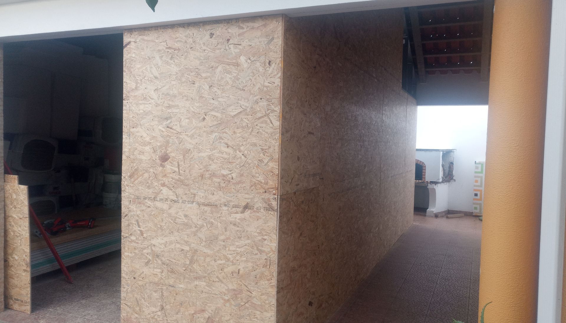 Porta de correr em painéis de madeira castanha clara, parcialmente aberta, no interior de um edifício.