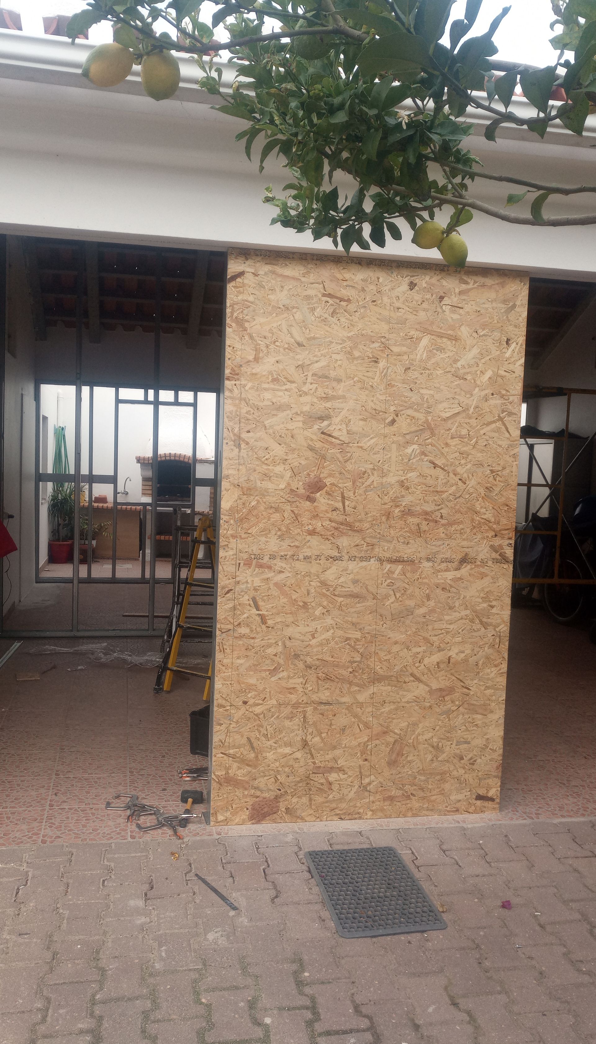 Painel de madeira bloqueando parcialmente uma porta, em um canteiro de obras.