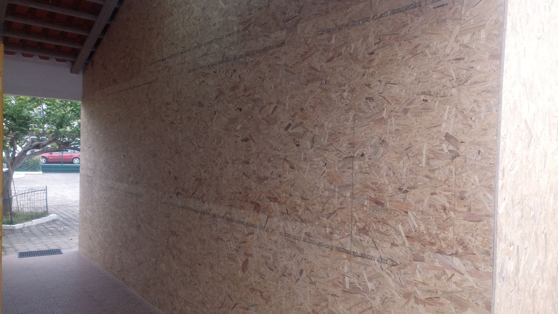 Parede externa feita de painéis de madeira composta sob um telhado de telhas.