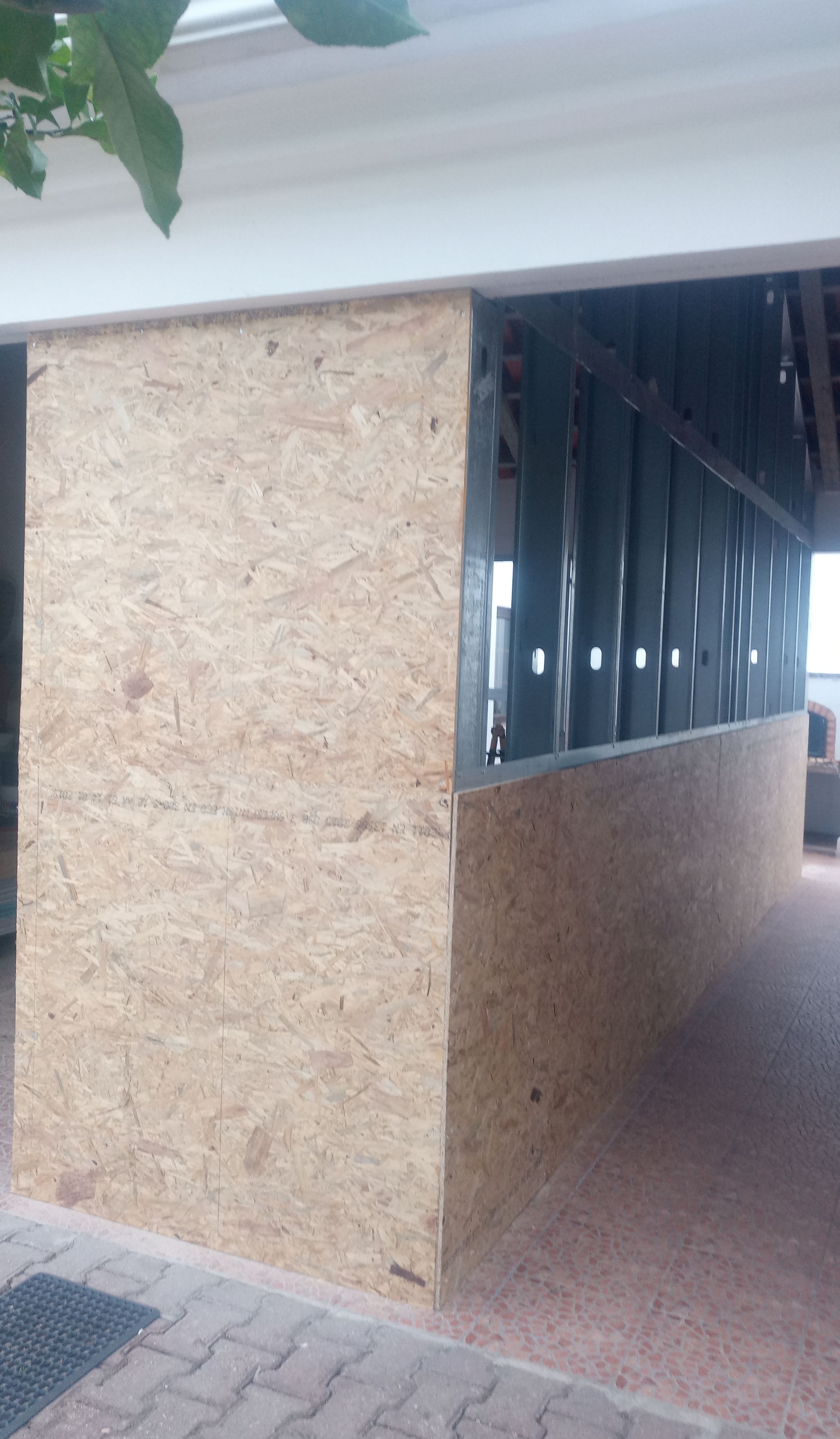 Vista exterior: Parede com painéis de madeira e estrutura metálica sob um toldo branco.