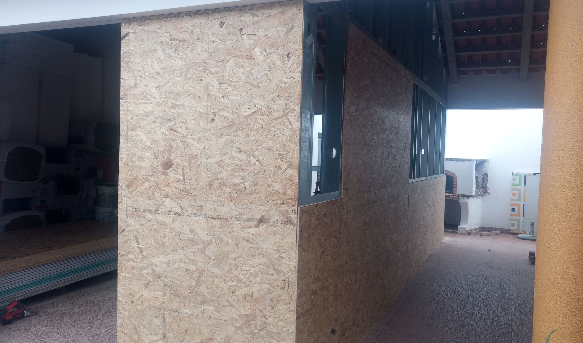 Paredes revestidas com OSB de um edifício em construção, com caixilhos de janelas e telhado aparentes.