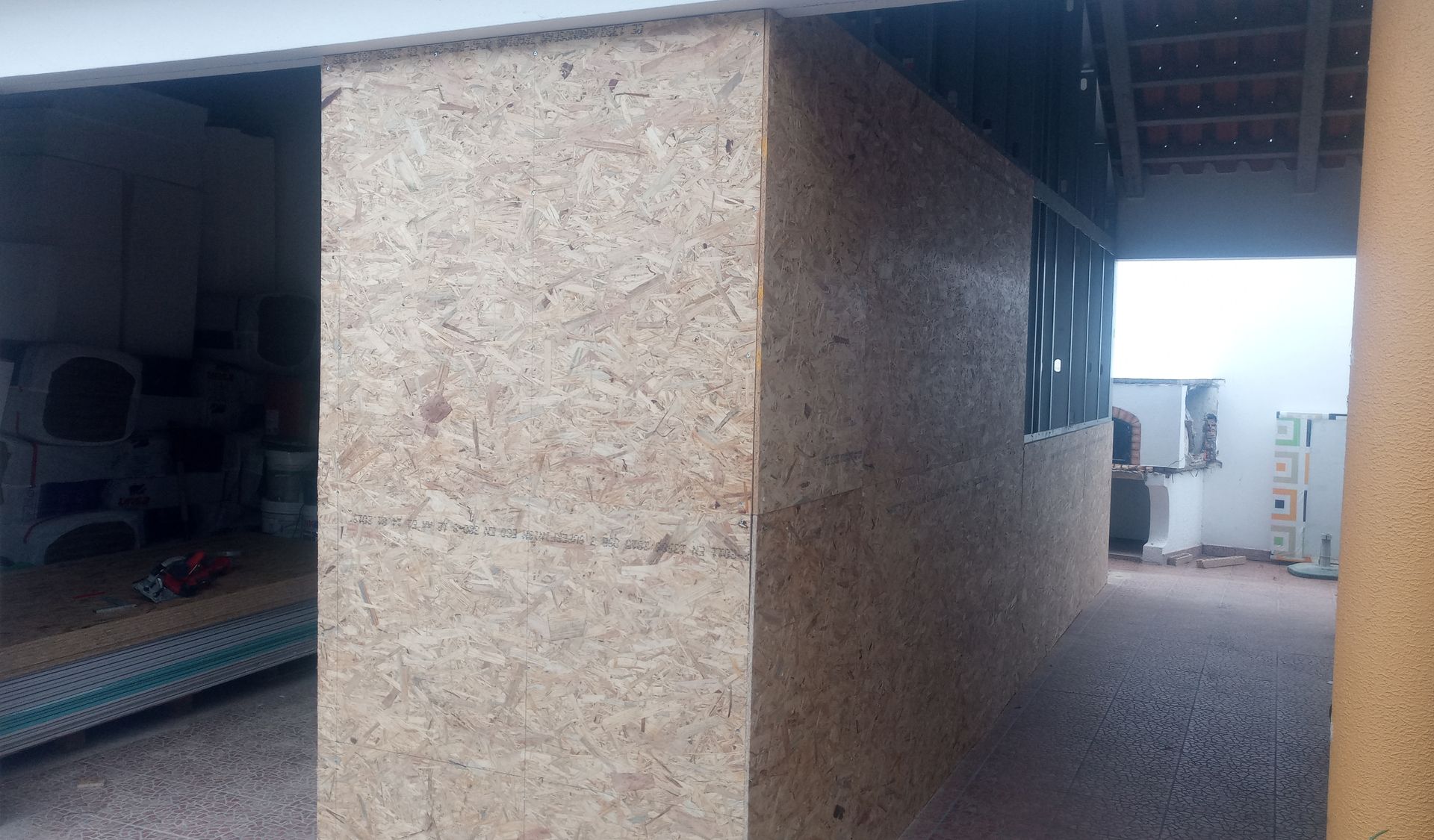 Vista interior de uma estrutura com paredes de madeira expostas e uma janela.